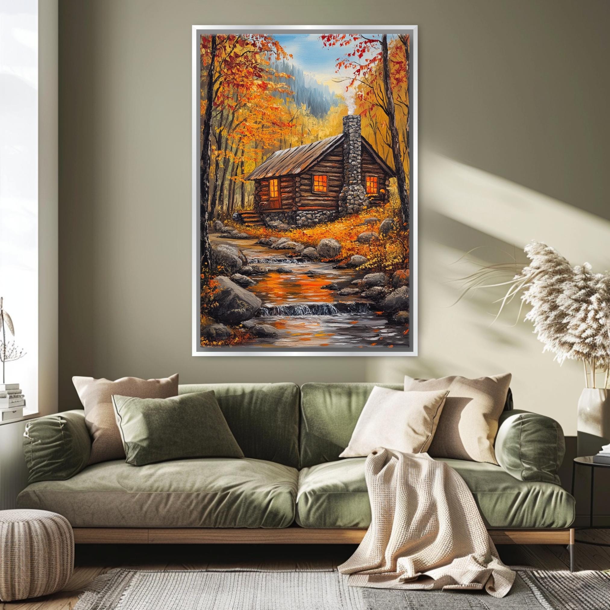 a cozy living room with a large painting of a cabin nestled in a forest, surrounded by autumn foliage. The painting is hung on the wall above a green sofa, which is adorned with throw pillows and a blanket. The room has a warm and inviting atmosphere, with natural light streaming in from a window and a potted plant adding a touch of greenery to the space.