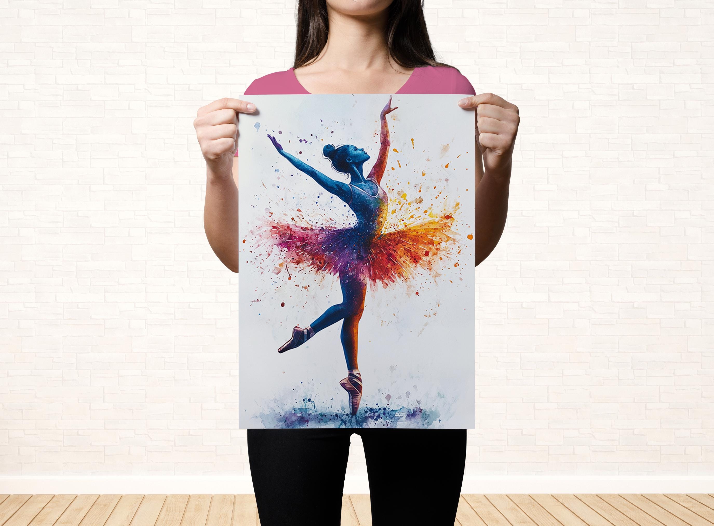 A woman is holding up a colorful painting of a ballerina in a tutu, with splashes of color on her costume.