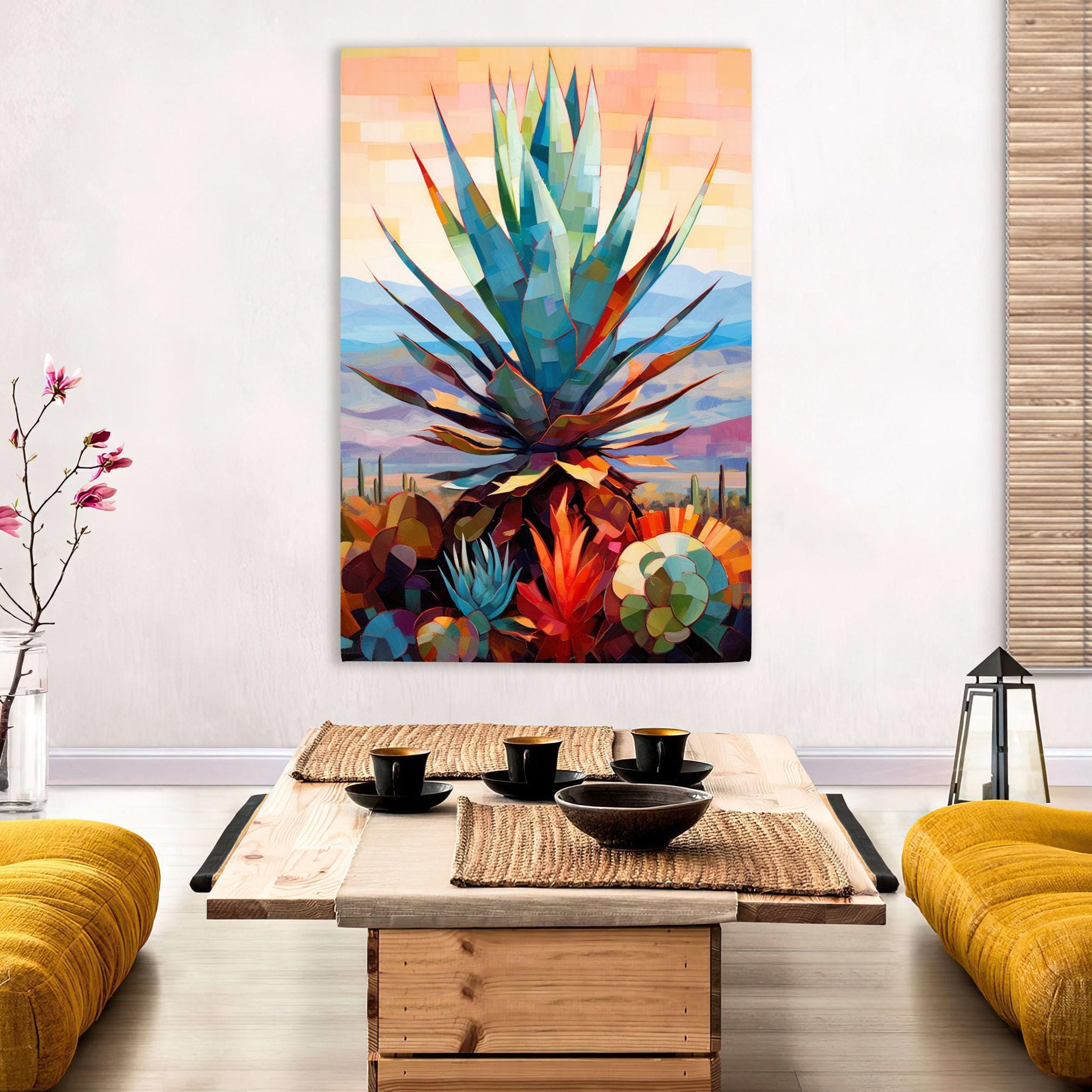 a vibrant, colorful painting of a desert landscape with a large cactus at the center, hanging on a wall above a wooden coffee table with a woven placemat.