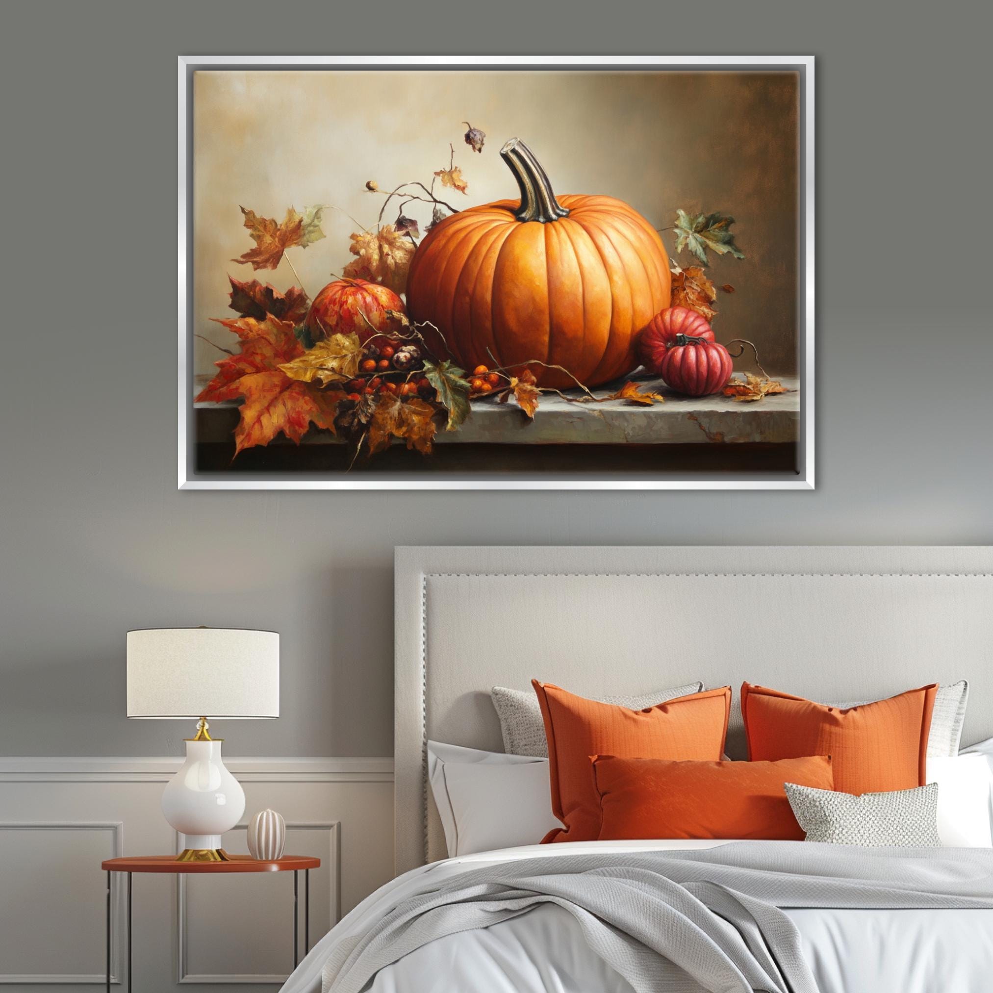 a large framed painting of a pumpkin and autumn leaves on a wall above a bed with orange pillows and a white headboard.