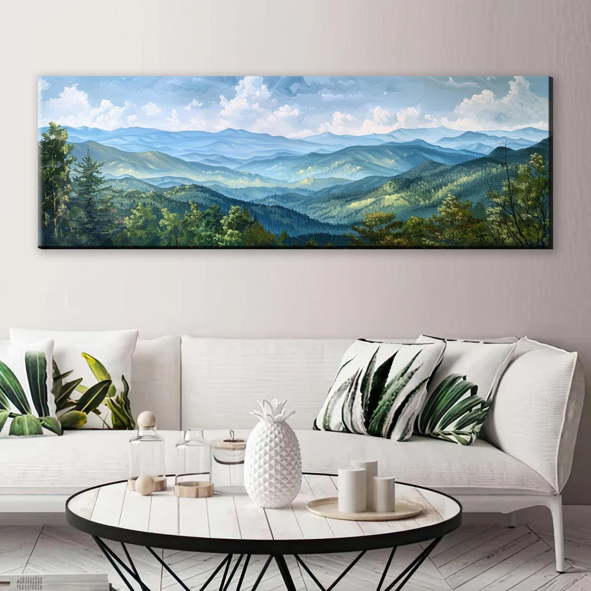 a large landscape painting hanging on a wall above a white sofa with decorative pillows.