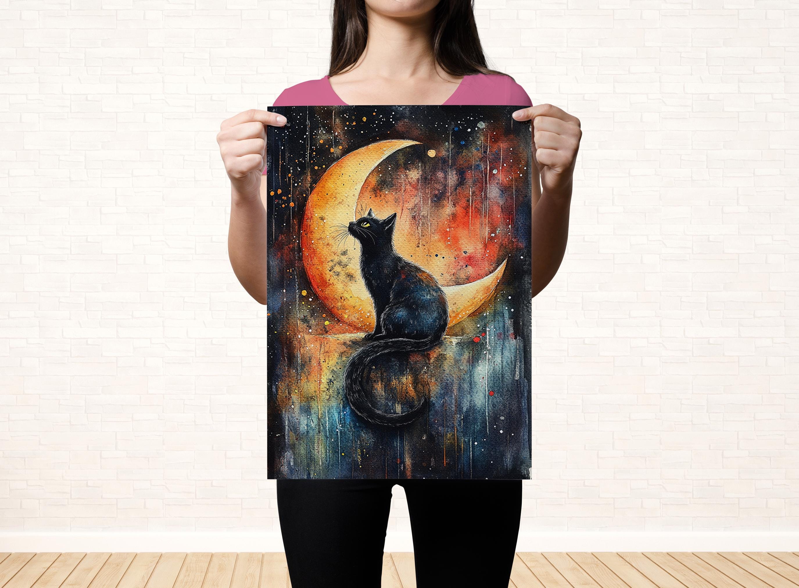 A woman holds up a vibrant painting depicting a black cat sitting on a crescent moon, gazing up at the night sky.