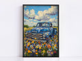 The image is a framed painting depicting an old blue pickup truck parked in a field of colorful wildflowers.