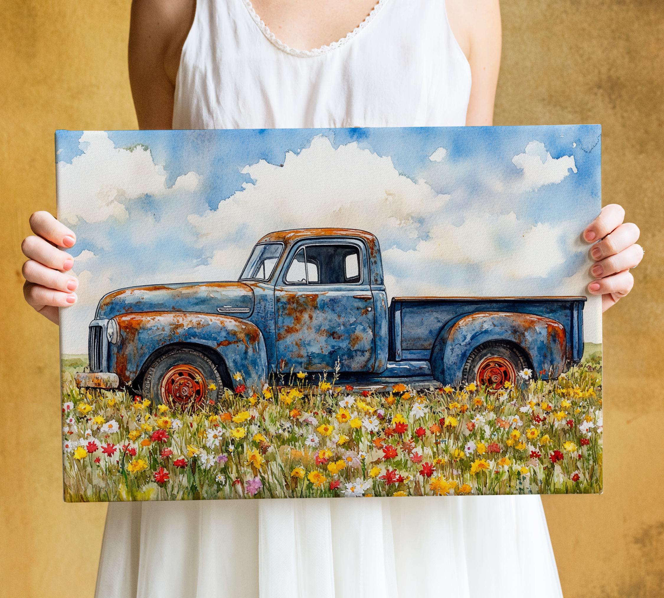 A woman holds a framed painting of an old, rusted blue truck parked in a field of colorful wildflowers.