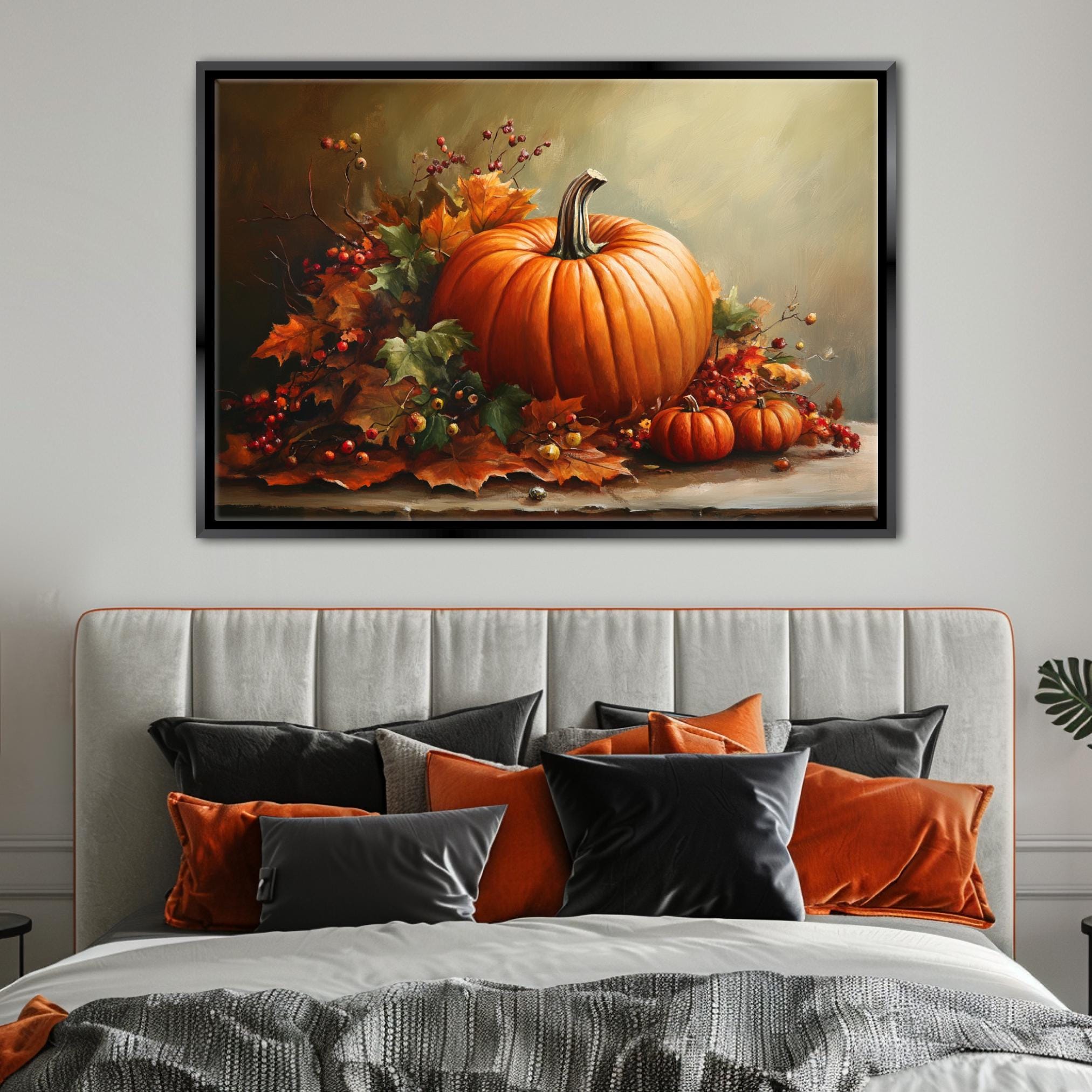 a large framed painting of a pumpkin and autumn leaves hanging above a bed with a gray headboard and black and orange pillows.
