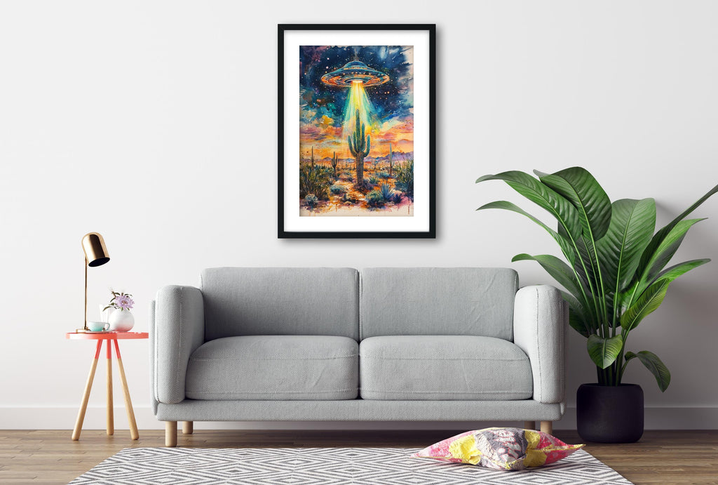 a gray sofa, a framed artwork of a cactus with an alien spacecraft hovering above it, and a potted plant on the floor.