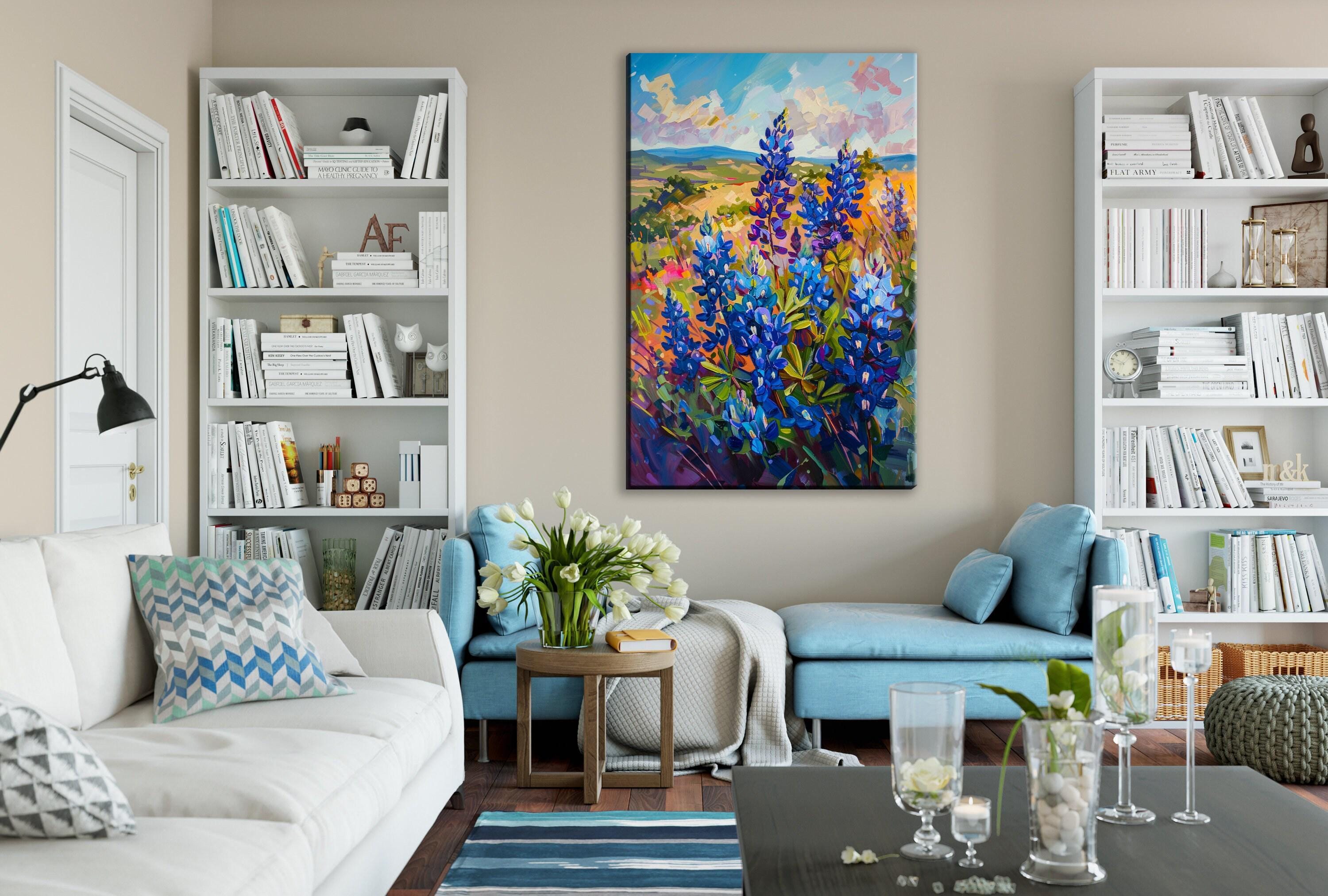 a cozy living room with a large painting of a field of colorful flowers hanging on the wall. The room is furnished with a white sofa, a blue armchair, and a wooden coffee table. The walls are decorated with white bookshelves, and the room is illuminated by a lamp and natural light coming through the window.