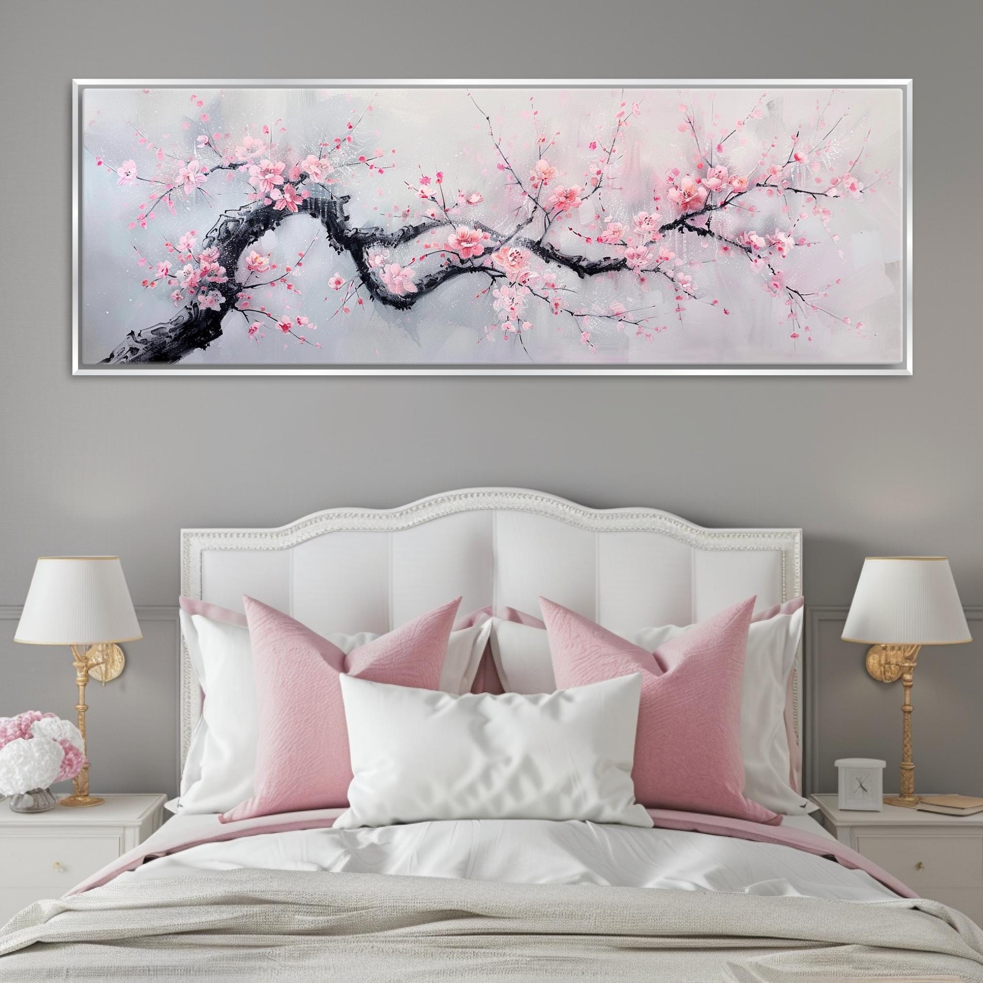 a white bed with pink pillows and a painting on the wall