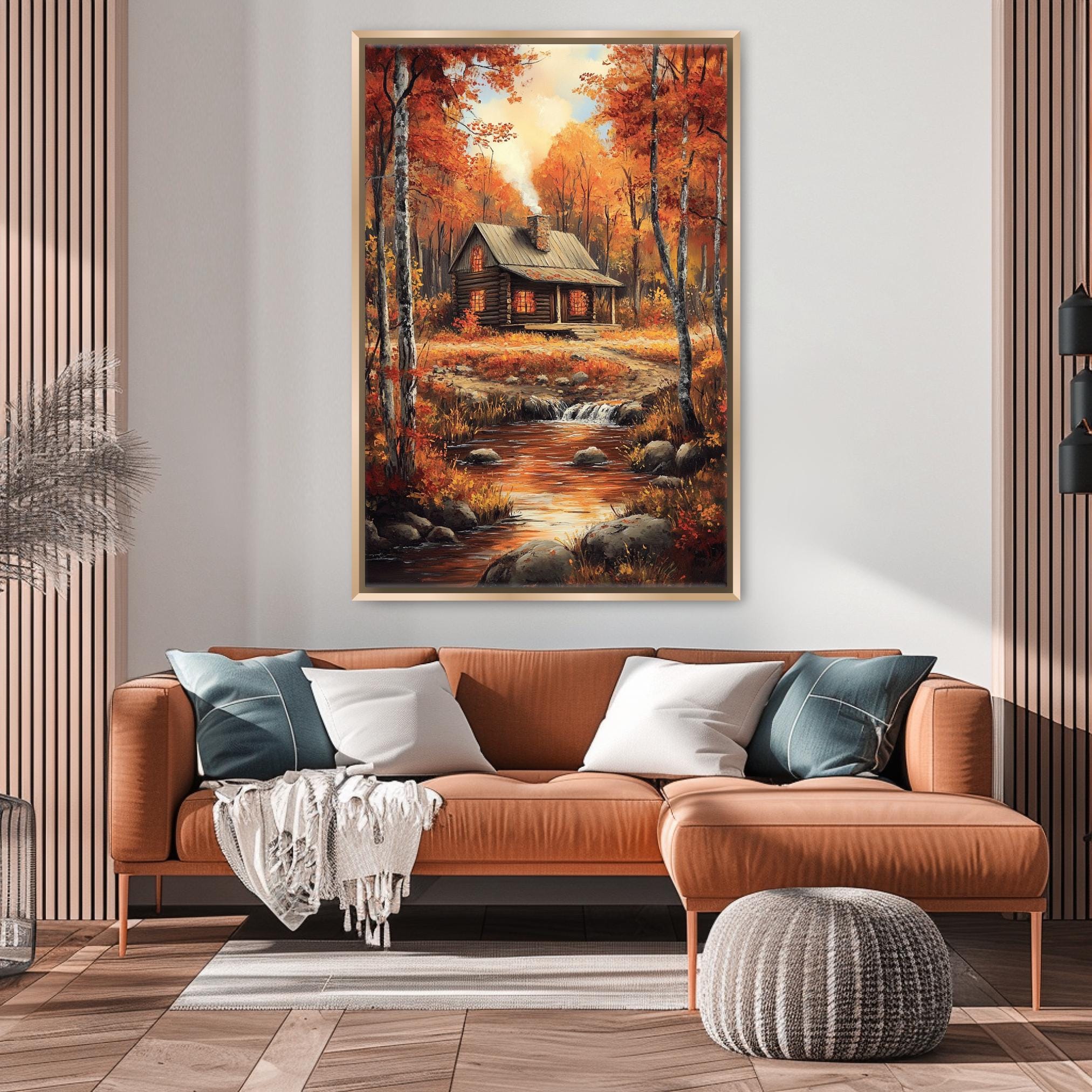 a cozy living room with a large painting of a cabin in the woods hanging on the wall above a brown sofa with pillows.