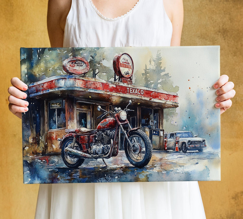 A person is holding a framed painting depicting a red motorcycle parked in front of a gas station with a car in the background.