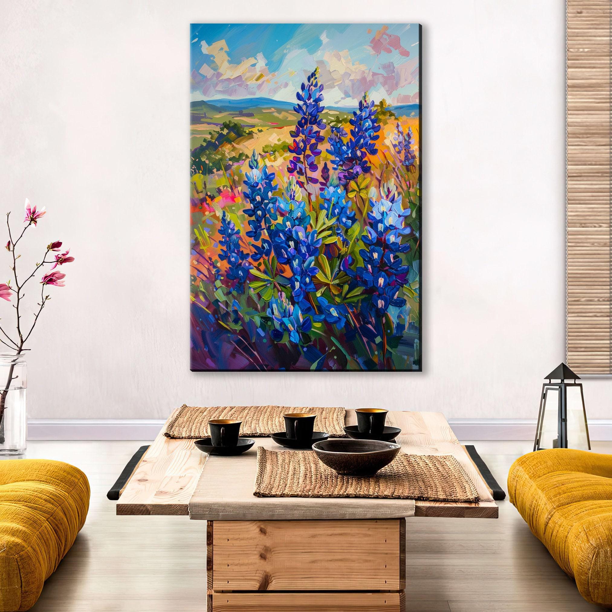a large painting of a field of blue flowers hanging on a wall above a wooden coffee table with a bowl and cups on it.