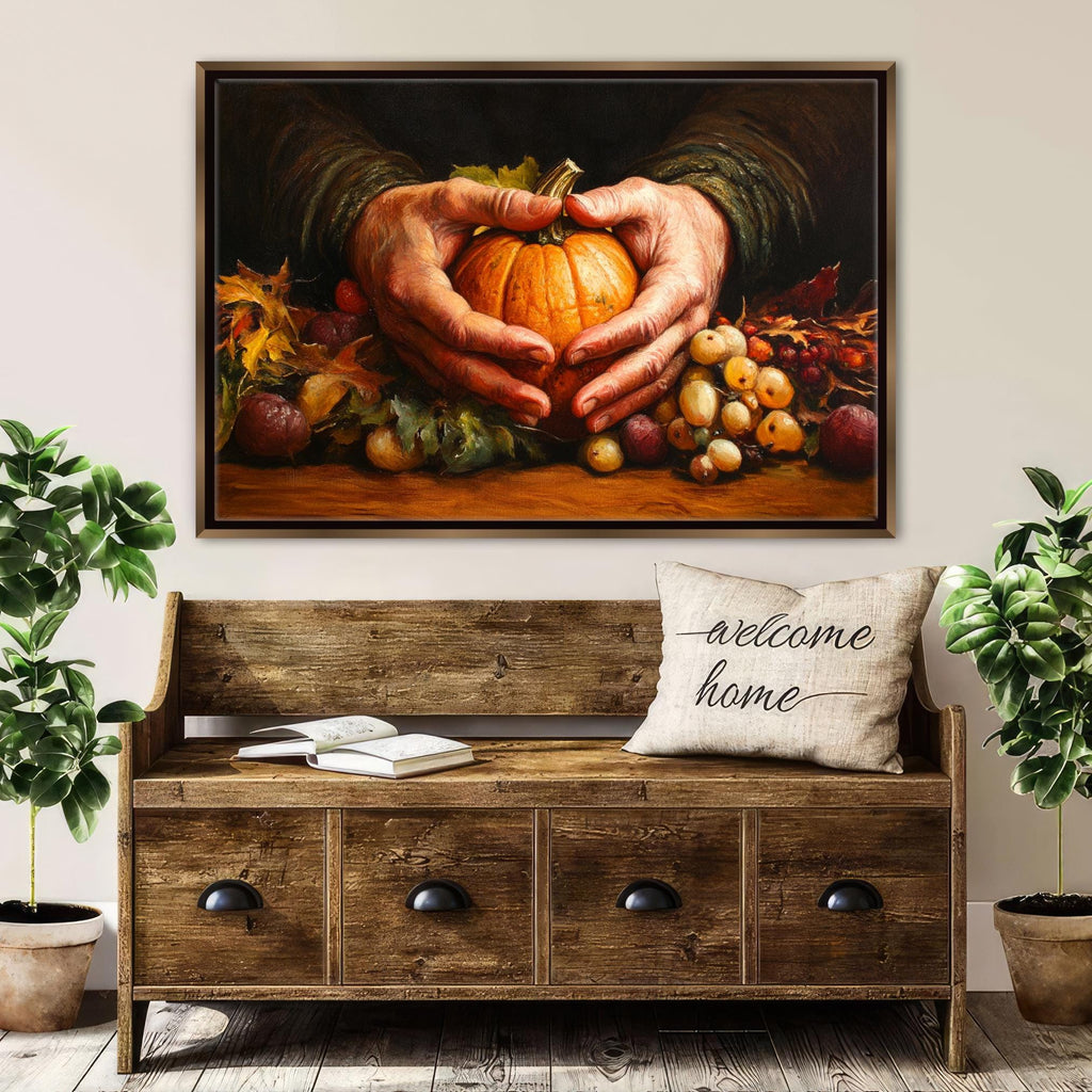 A wooden bench with a "welcome home" pillow sits in front of a framed painting depicting a pair of hands holding a pumpkin and surrounded by autumn fruits and vegetables.