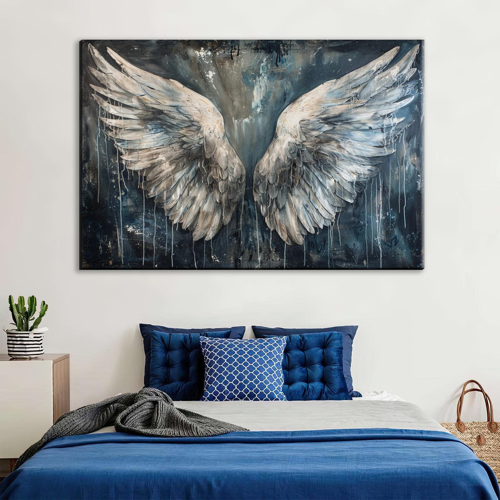 a large painting of angel wings hanging above a bed with blue bedding and pillows.