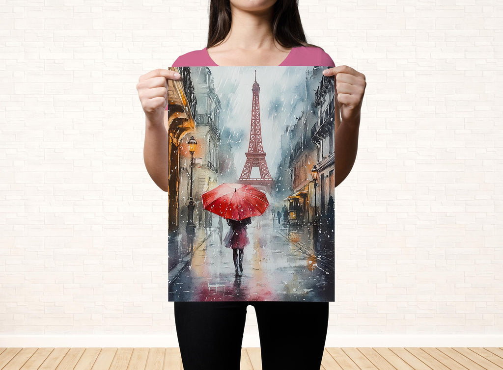A woman holds up a framed painting depicting a rainy scene with a person walking under an umbrella in front of the Eiffel Tower.