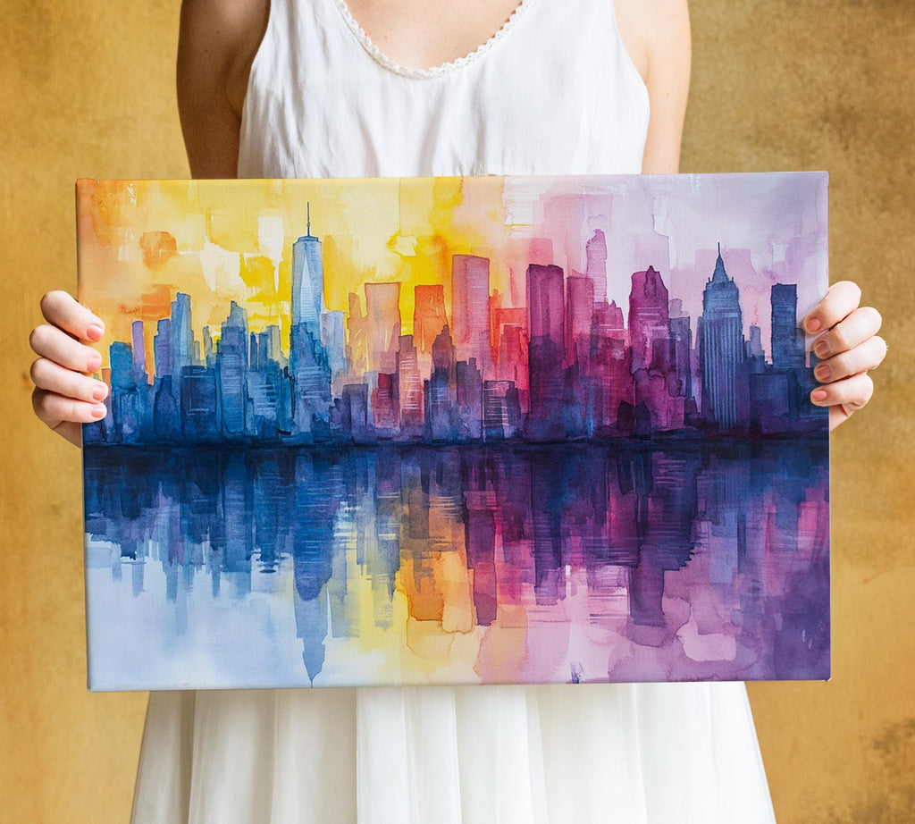 A person is holding up a colorful painting depicting a city skyline, with the buildings rendered in various shades of blue, purple, and yellow.