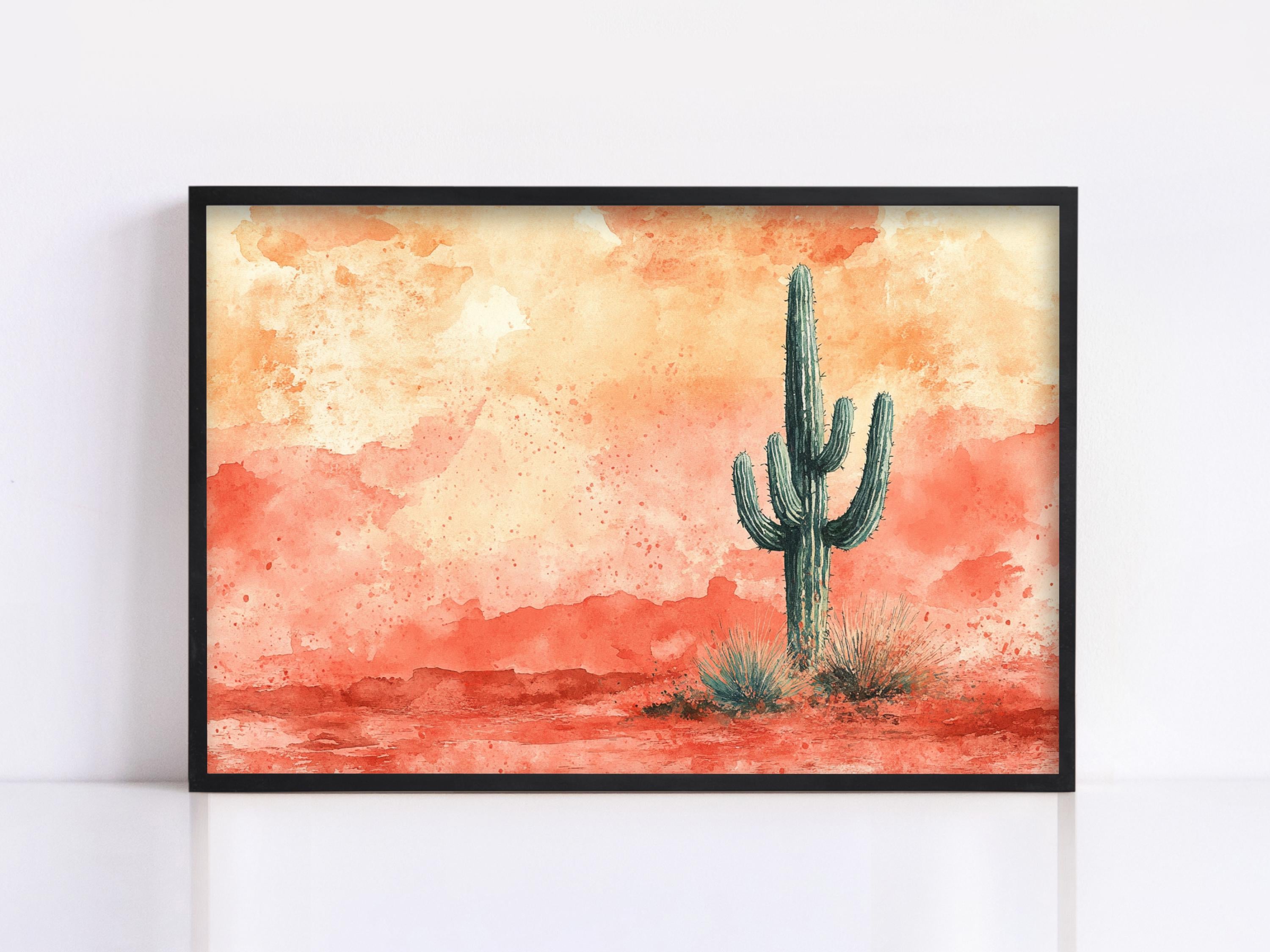 A framed watercolor painting depicting a cactus in a desert landscape with a warm, orange and red background.
