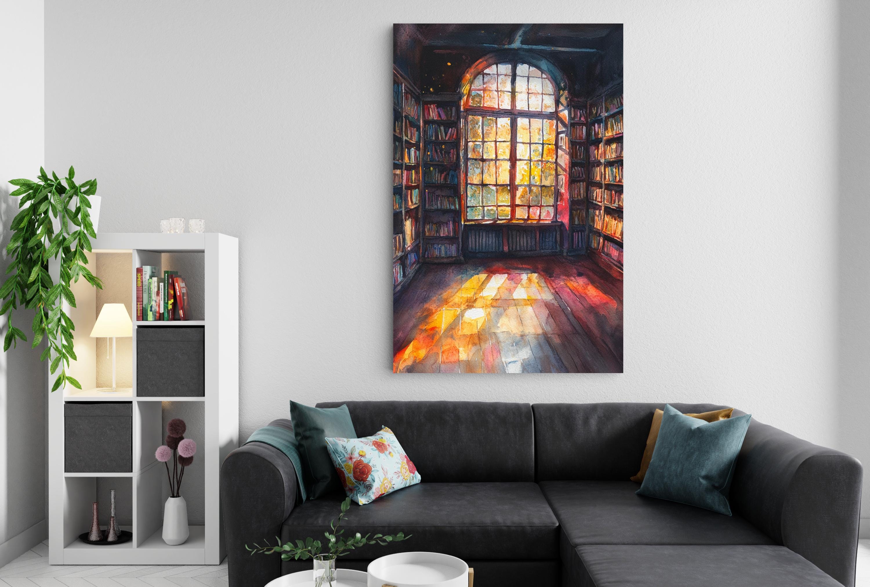 a cozy living room with a large window that allows natural light to flood the space. The room is furnished with a black sofa and a bookshelf filled with books. A potted plant and a vase of flowers add to the room's decor. The walls are painted white, and a large painting of a library or book-filled room hangs above the sofa, creating a warm and inviting atmosphere.