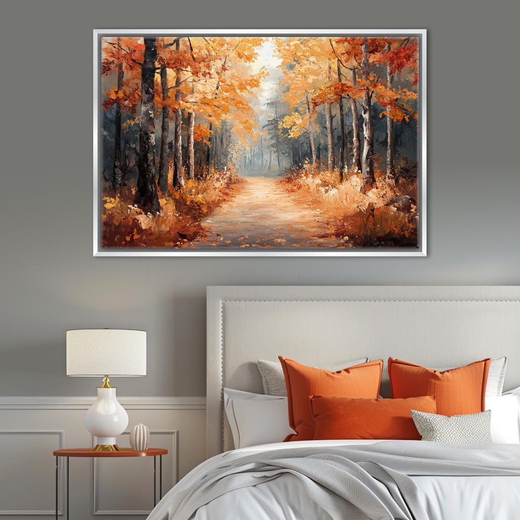 a serene autumn scene with a path lined by trees on the left side, leading to a clearing in the distance. The trees are adorned with vibrant orange leaves, creating a warm and inviting atmosphere. The painting is hung on a gray wall above a bed with white pillows and a gray headboard.