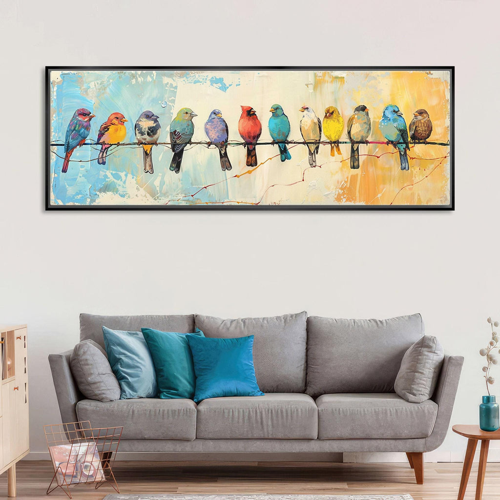 a large painting of colorful birds perched on a wire, hanging on a wall above a gray couch with blue pillows.
