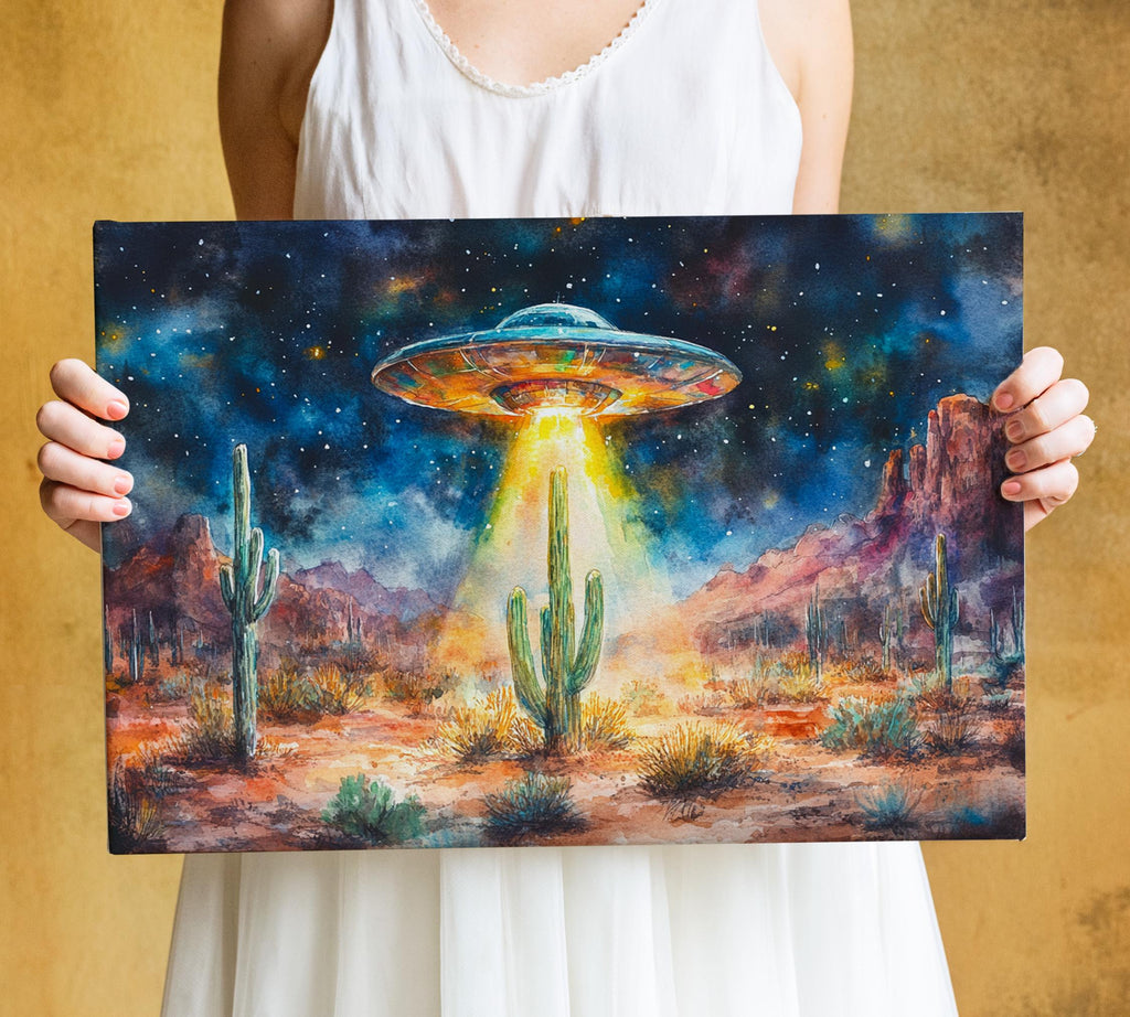 A person is holding a framed painting depicting a desert landscape with a large alien spacecraft hovering above the cacti and mountains.