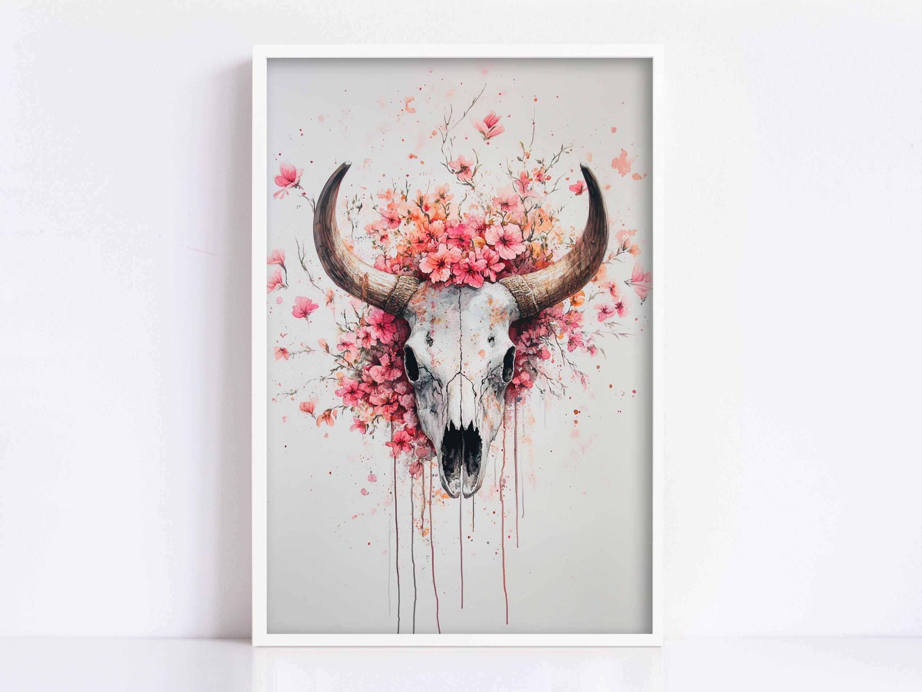 A framed artwork depicting a skull with large horns surrounded by pink flowers and dripping with paint.
