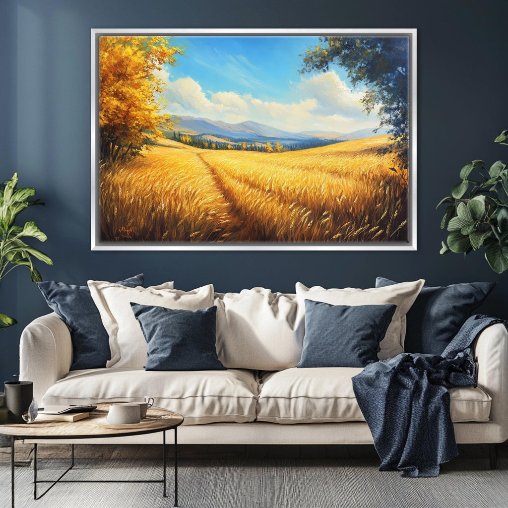 a large painting of a field with golden wheat against a blue sky with clouds, hanging on a wall above a white sofa with blue throw pillows.