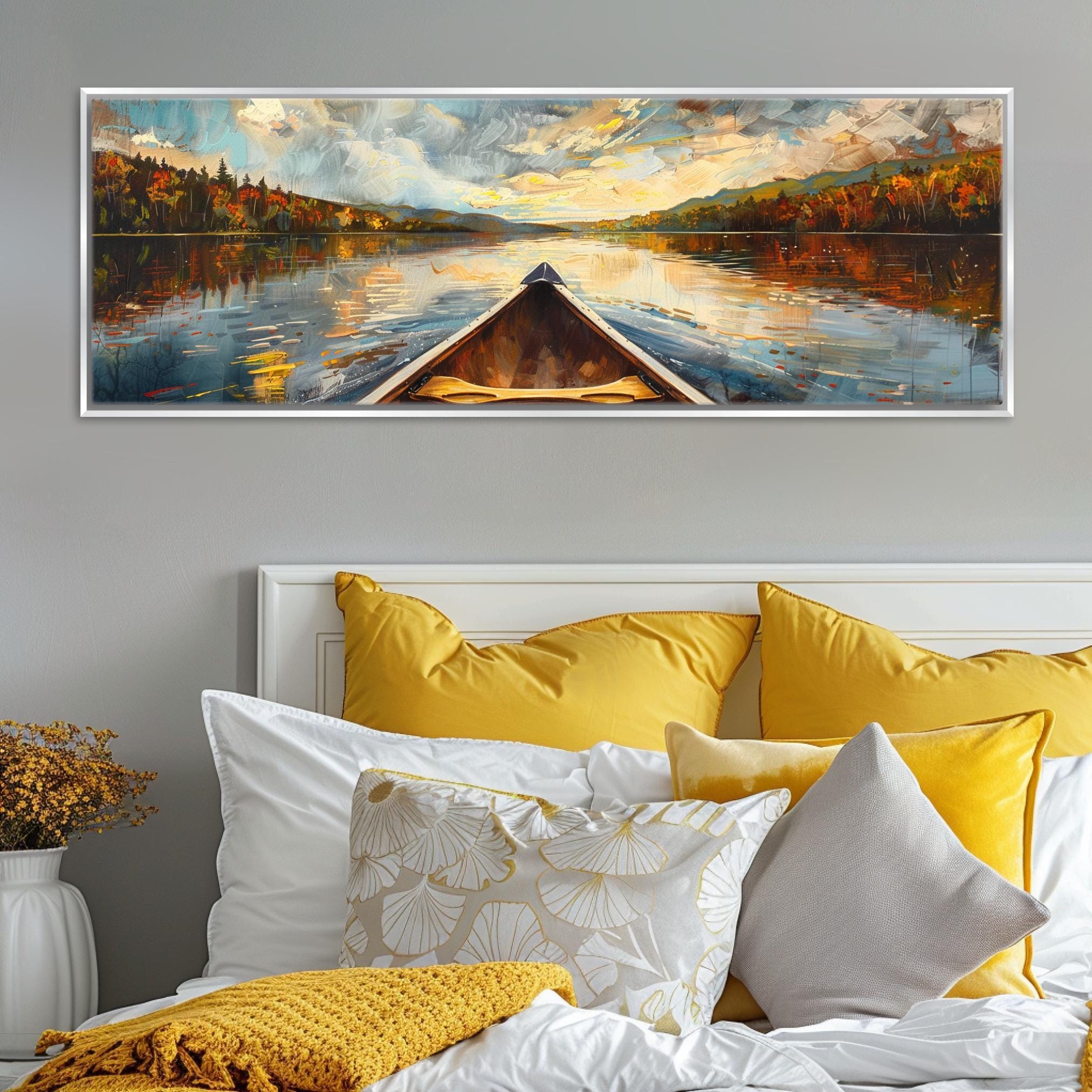 a large painting of a boat on a lake, with a scenic landscape in the background. The painting is displayed on a wall above a bed with yellow and white pillows.