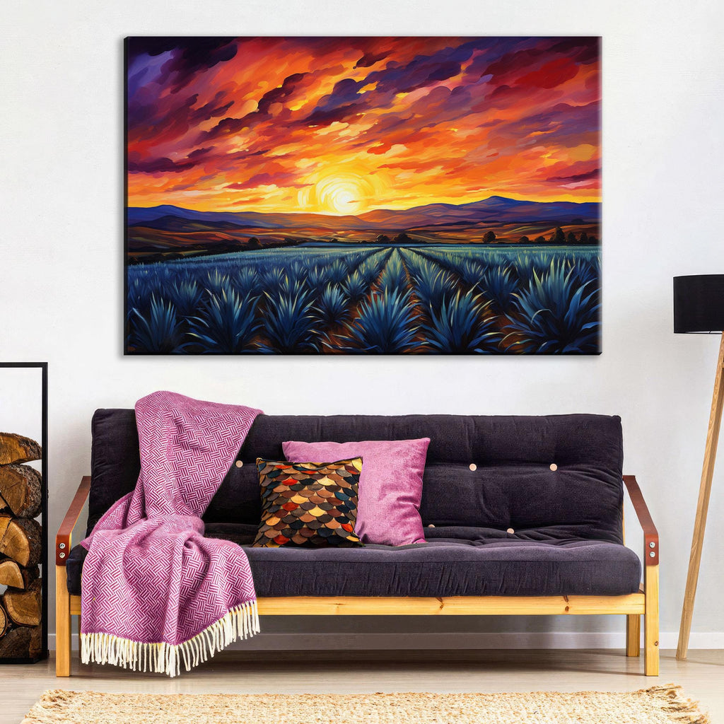 a large painting of a sunset over a field of blue agave plants, hanging on a wall above a black couch with colorful throw pillows.