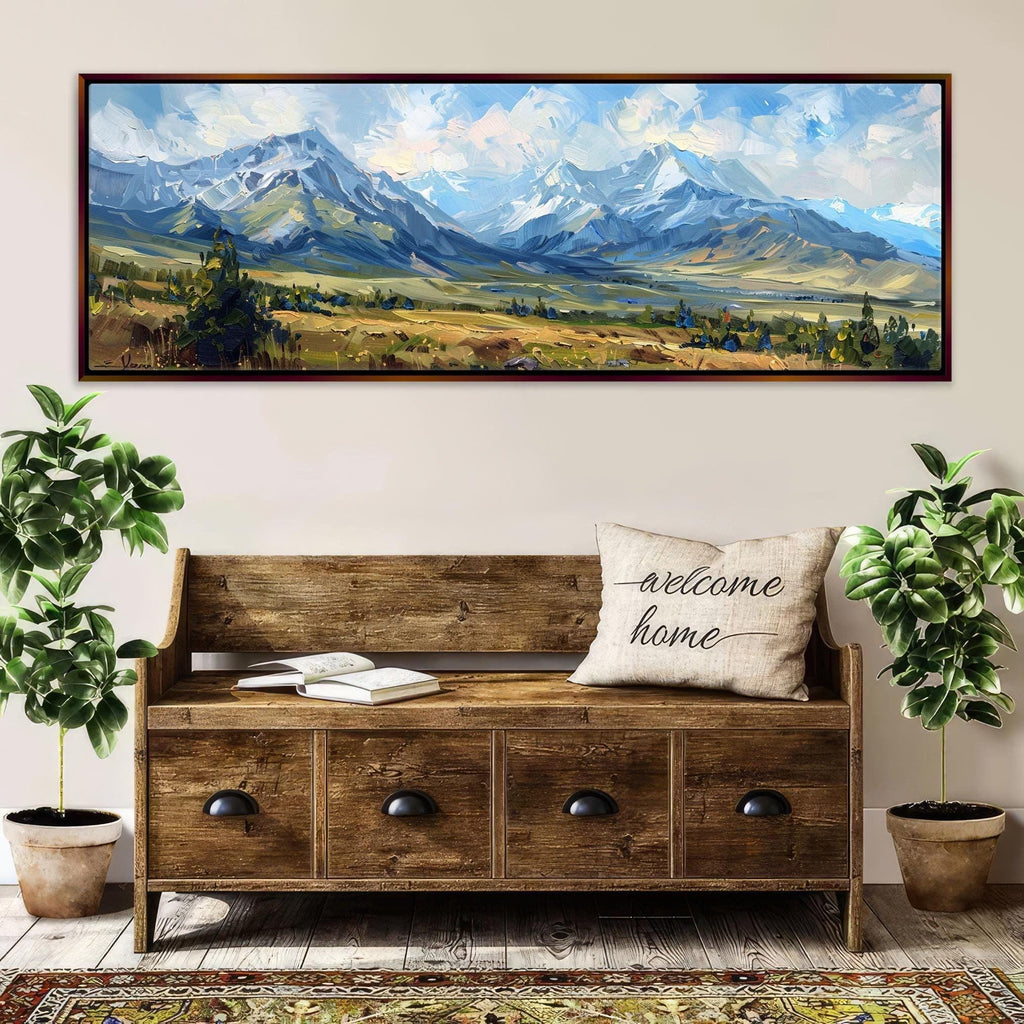 a large wooden bench with a "welcome home" pillow, surrounded by potted plants and a framed landscape painting depicting a mountainous, forested area.