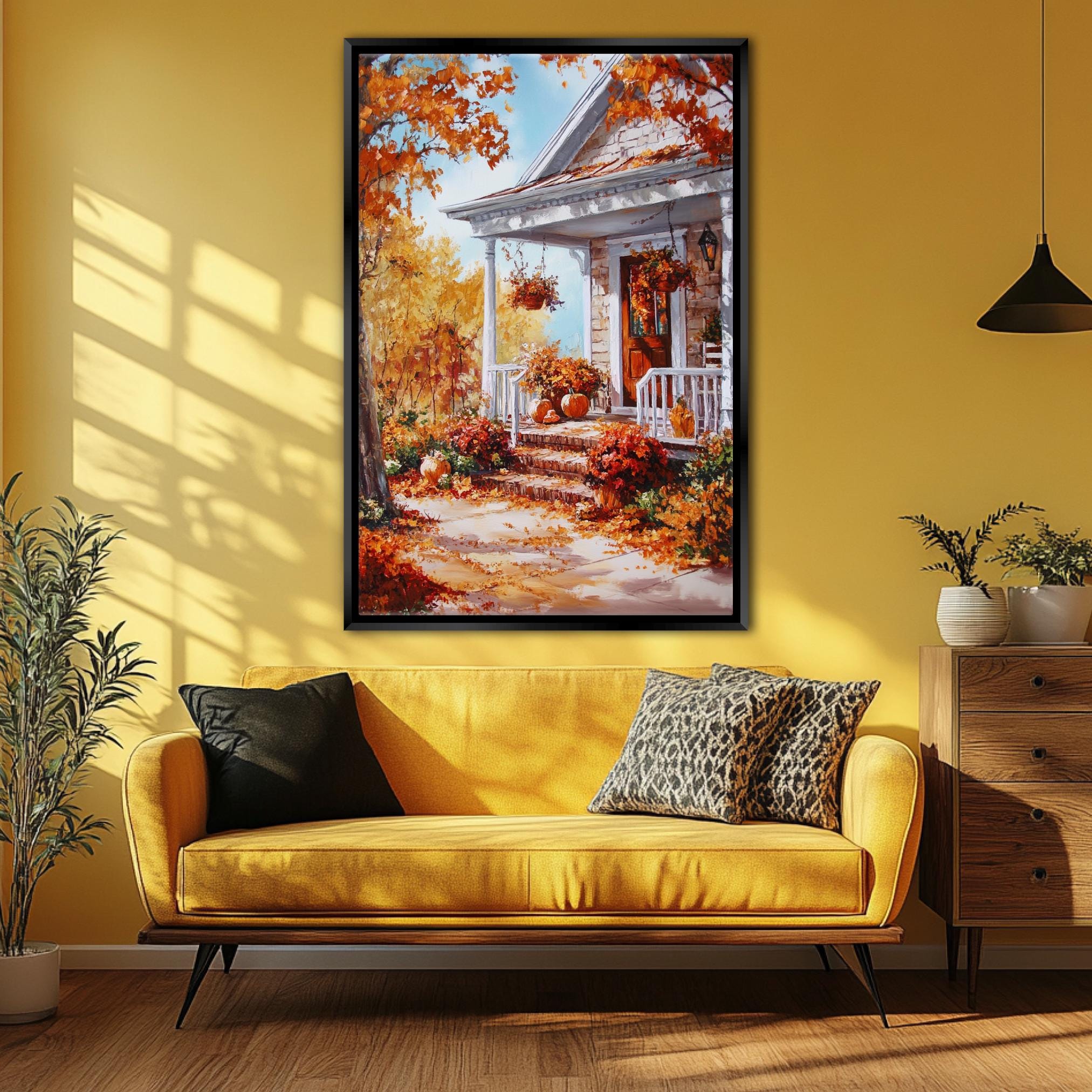 a cozy living room with a large, vibrant painting of a house with a porch and autumn foliage hanging on the wall above a yellow sofa with decorative pillows.