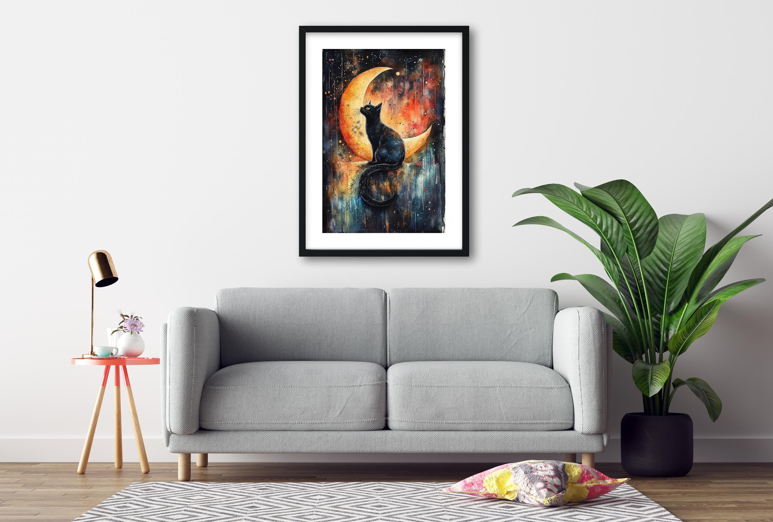 a gray sofa, a framed painting of a cat on a crescent moon, a potted plant, and a small table with a lamp.