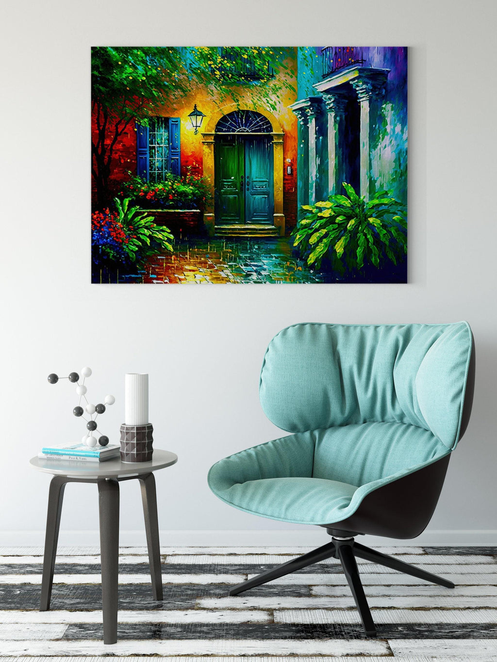 a vibrant painting of a colorful house with a green door, set against a backdrop of lush greenery and flowers. The painting is hung on a white wall above a modern chair and a small side table, creating a cozy and inviting atmosphere in the room.