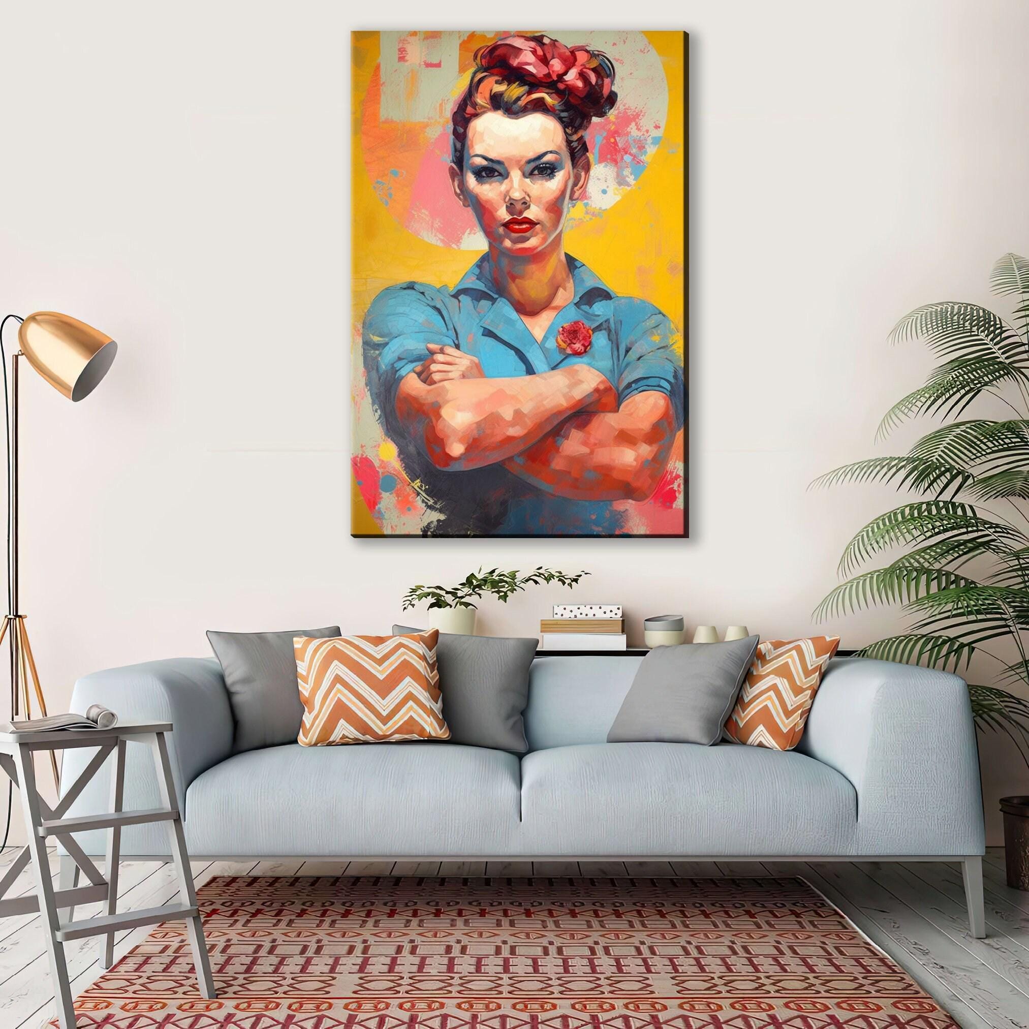 a large, colorful painting of a woman with a determined expression, hanging on a wall above a gray couch with patterned pillows.
