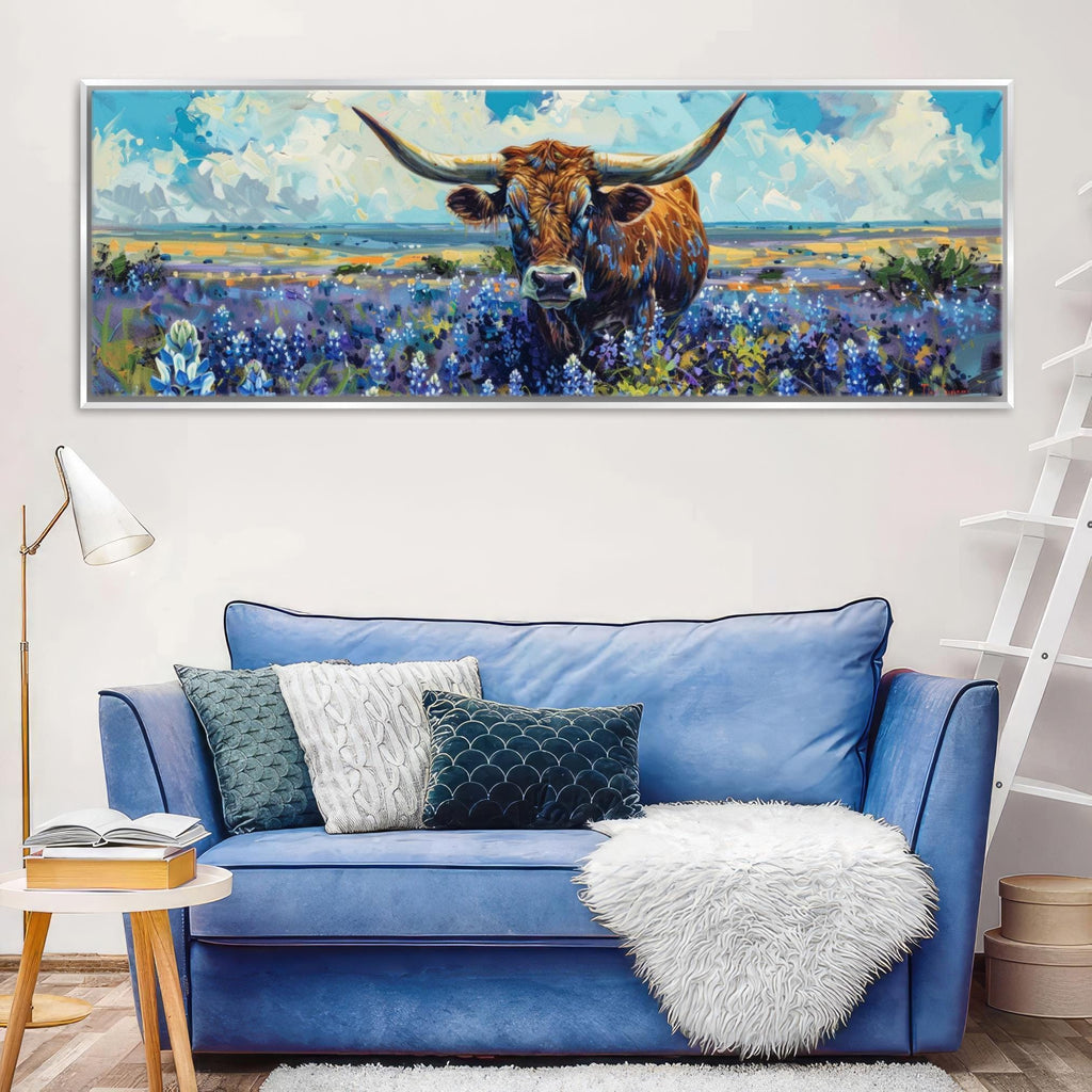 a large painting of a bull with horns, set against a field of flowers, hanging on a wall above a blue couch with pillows.