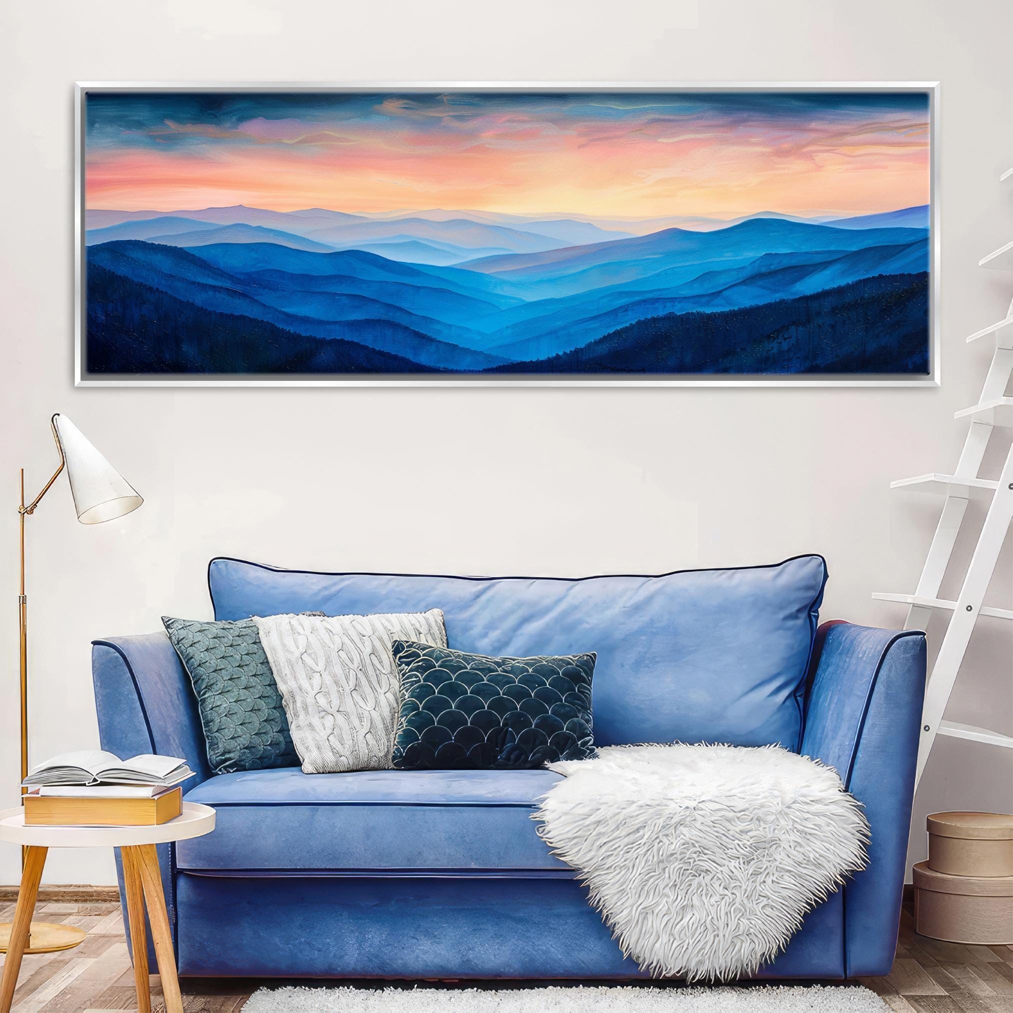 a blue sofa with white throw pillows, a white shag rug, and a framed landscape painting depicting a mountain range at sunset.