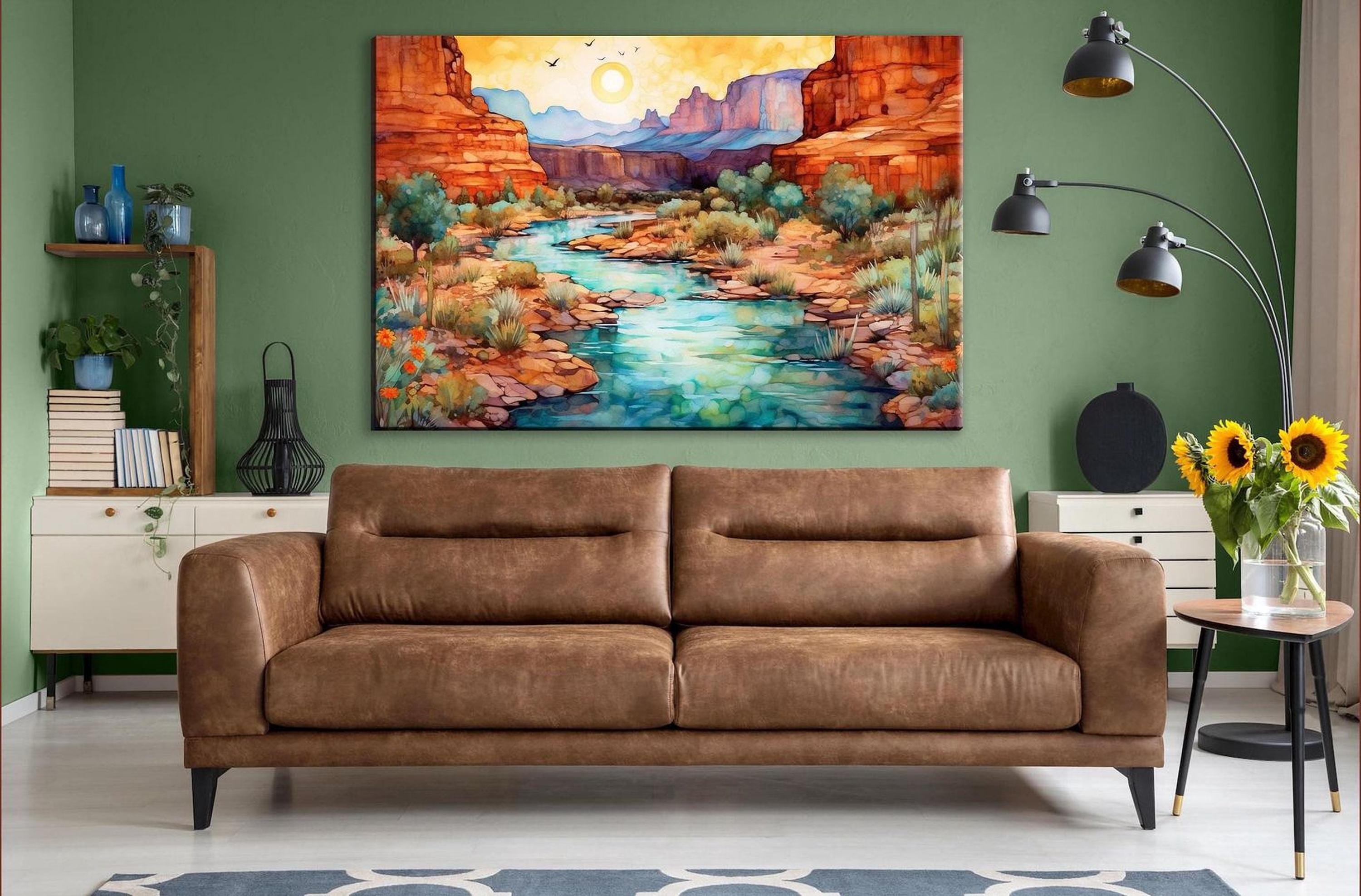 a large, colorful painting of a desert landscape hanging on a green wall above a brown leather couch in a cozy living room setting.