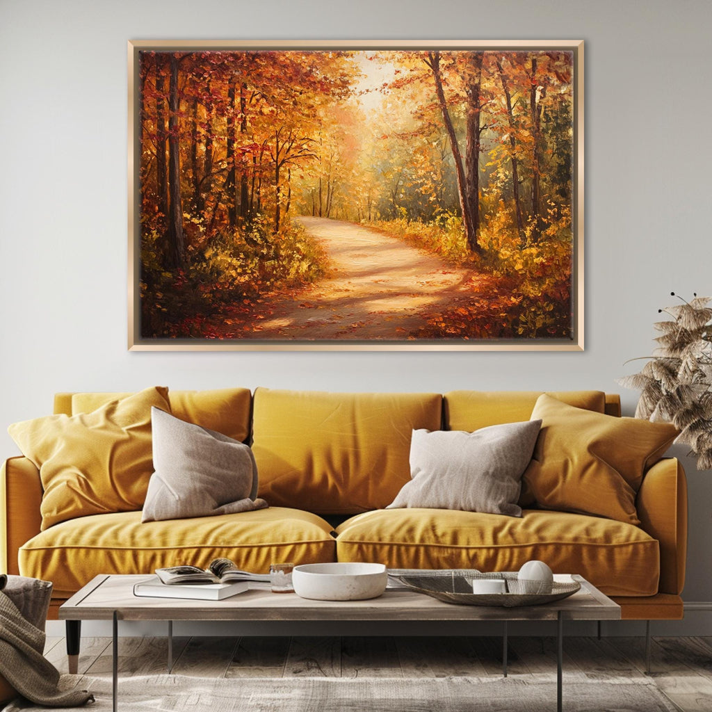 a cozy living room with a large, framed painting of a forest path with autumn foliage hanging above a yellow sofa. The painting is positioned above a wooden coffee table, which has a bowl and a book on it. The room has a neutral color scheme with a warm, inviting atmosphere.