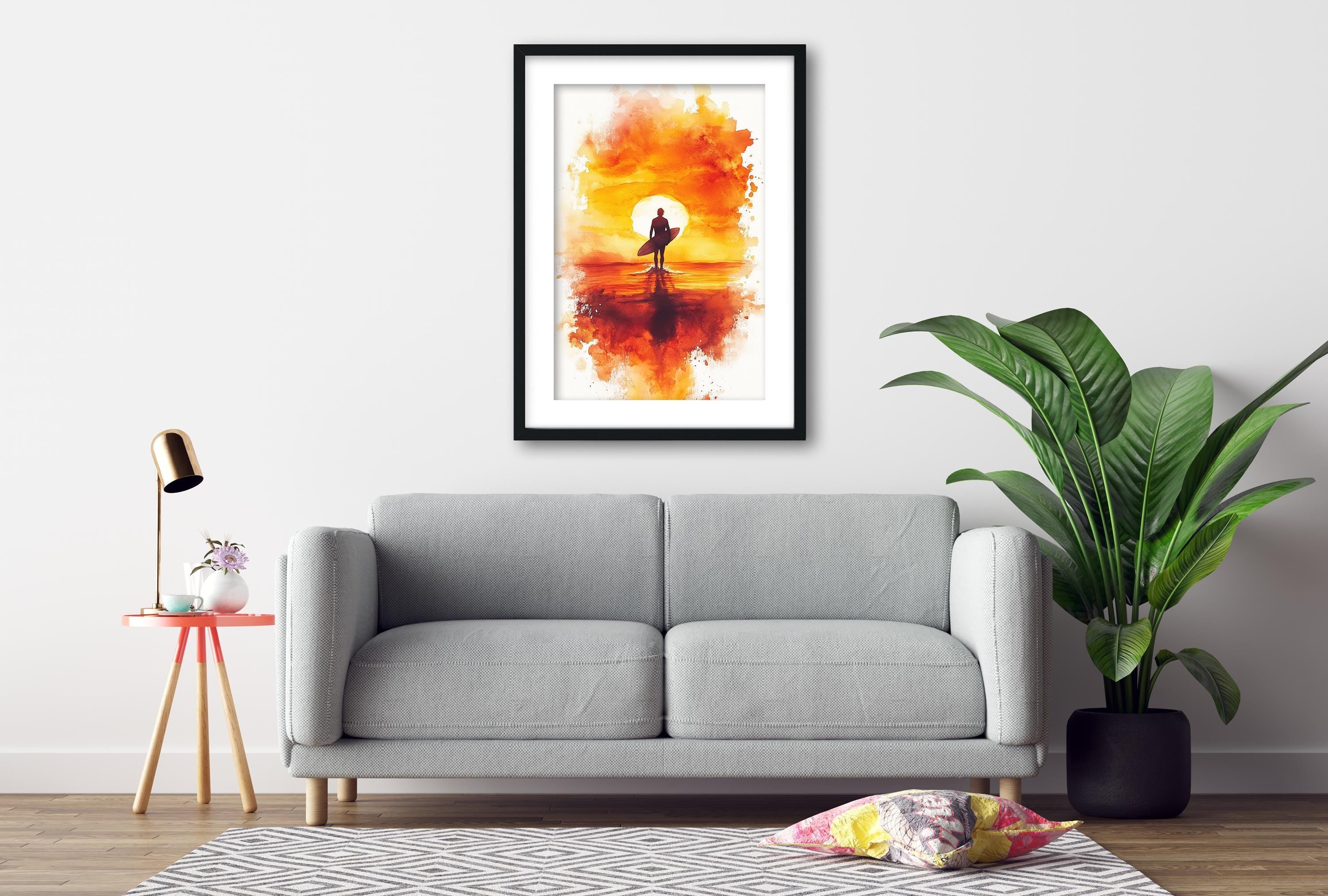 a gray sofa, a framed painting of a surfer on a sunset, a potted plant, and a small table with a lamp.