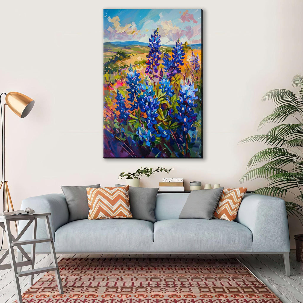 a large painting of a field of blue flowers hanging on a wall above a gray couch with orange and gray throw pillows.