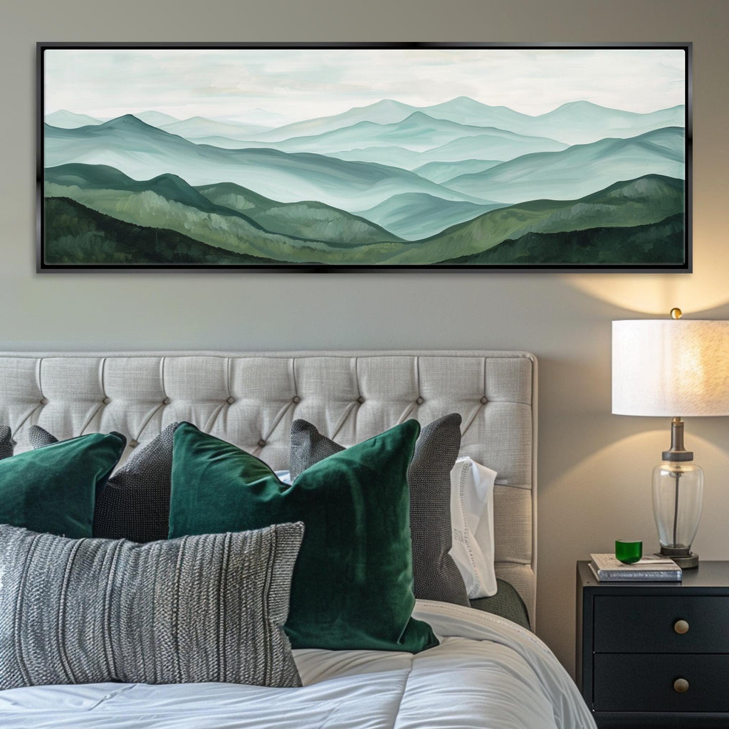 a serene bedroom scene with a large painting of a mountain landscape hanging above a tufted white headboard. The painting features a blend of green and gray tones, creating a calming and natural ambiance. The room is furnished with a tufted white headboard, a nightstand with a lamp, and a bed adorned with green and gray pillows.