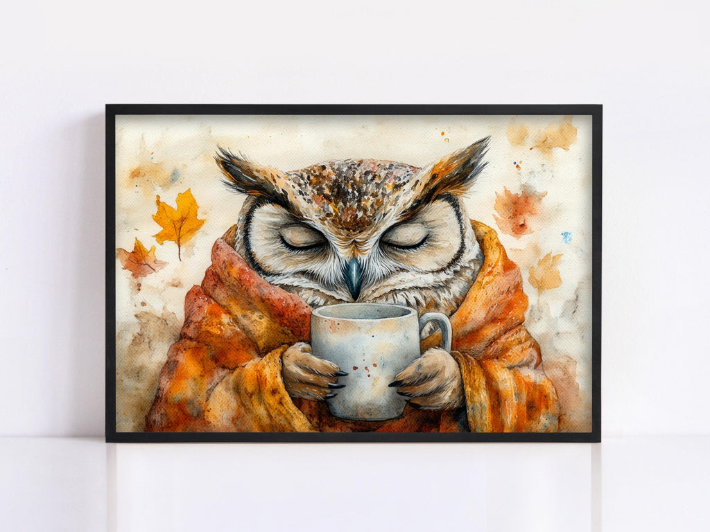 A framed painting depicting an owl wrapped in a blanket and holding a mug, with autumn leaves in the background.