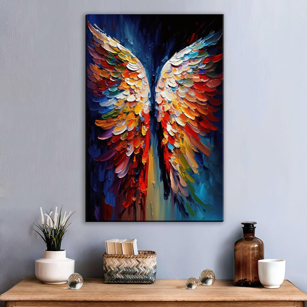 a vibrant, colorful painting of a pair of wings, hanging on a wall above a wooden table. The painting is surrounded by various decorative items, including a vase with white flowers, a woven basket, and a bottle.