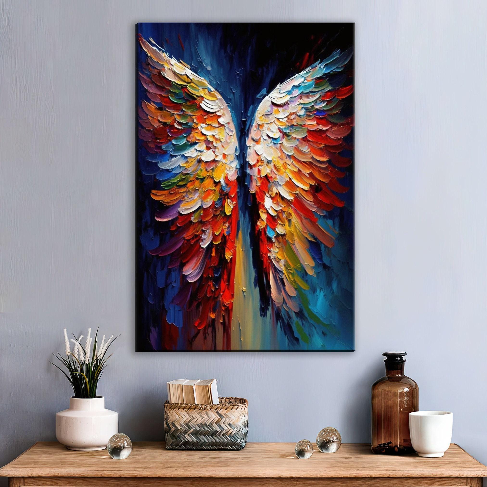 a vibrant, colorful painting of a pair of wings, hanging on a wall above a wooden table. The painting is surrounded by various decorative items, including a vase with white flowers, a woven basket, and a bottle.