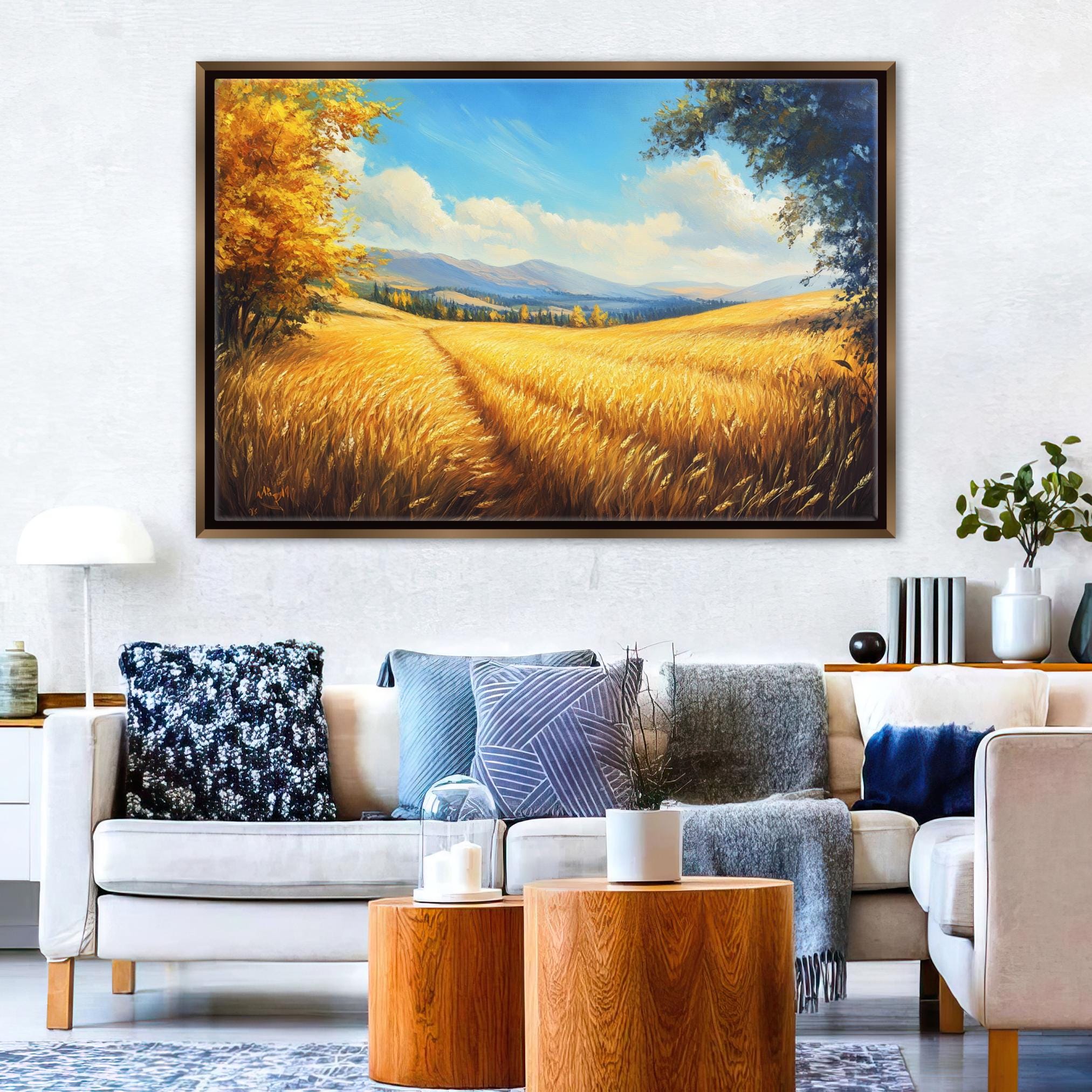 a large painting of a field with golden wheat, hanging on a wall above a white sofa with various throw pillows.