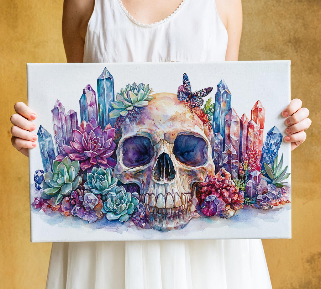 A person is holding a canvas with a colorful painting of a skull surrounded by various flowers, including succulents and other plants.