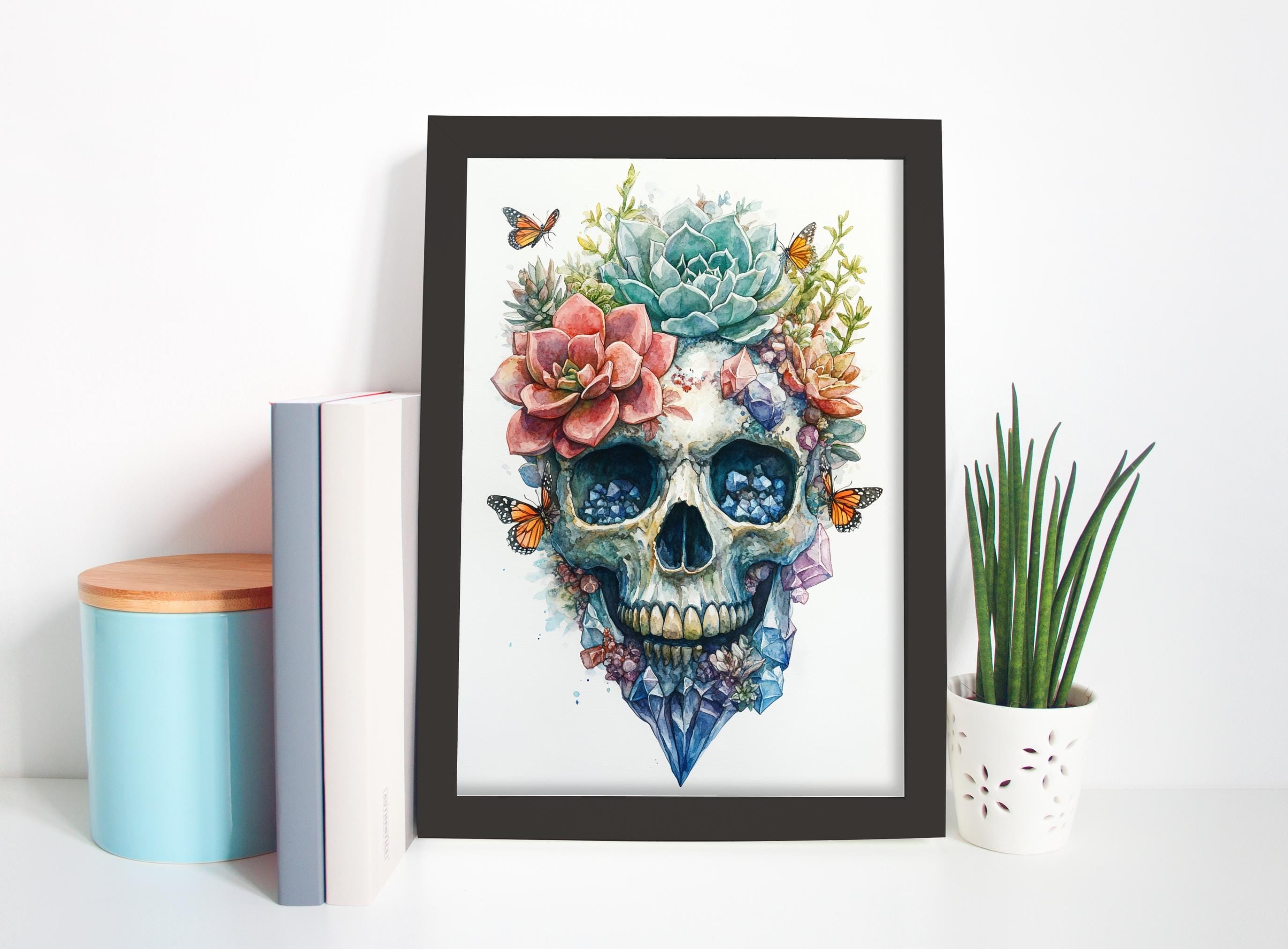 a framed artwork of a colorful skull with flowers and butterflies, placed on a shelf next to a potted plant and some books.