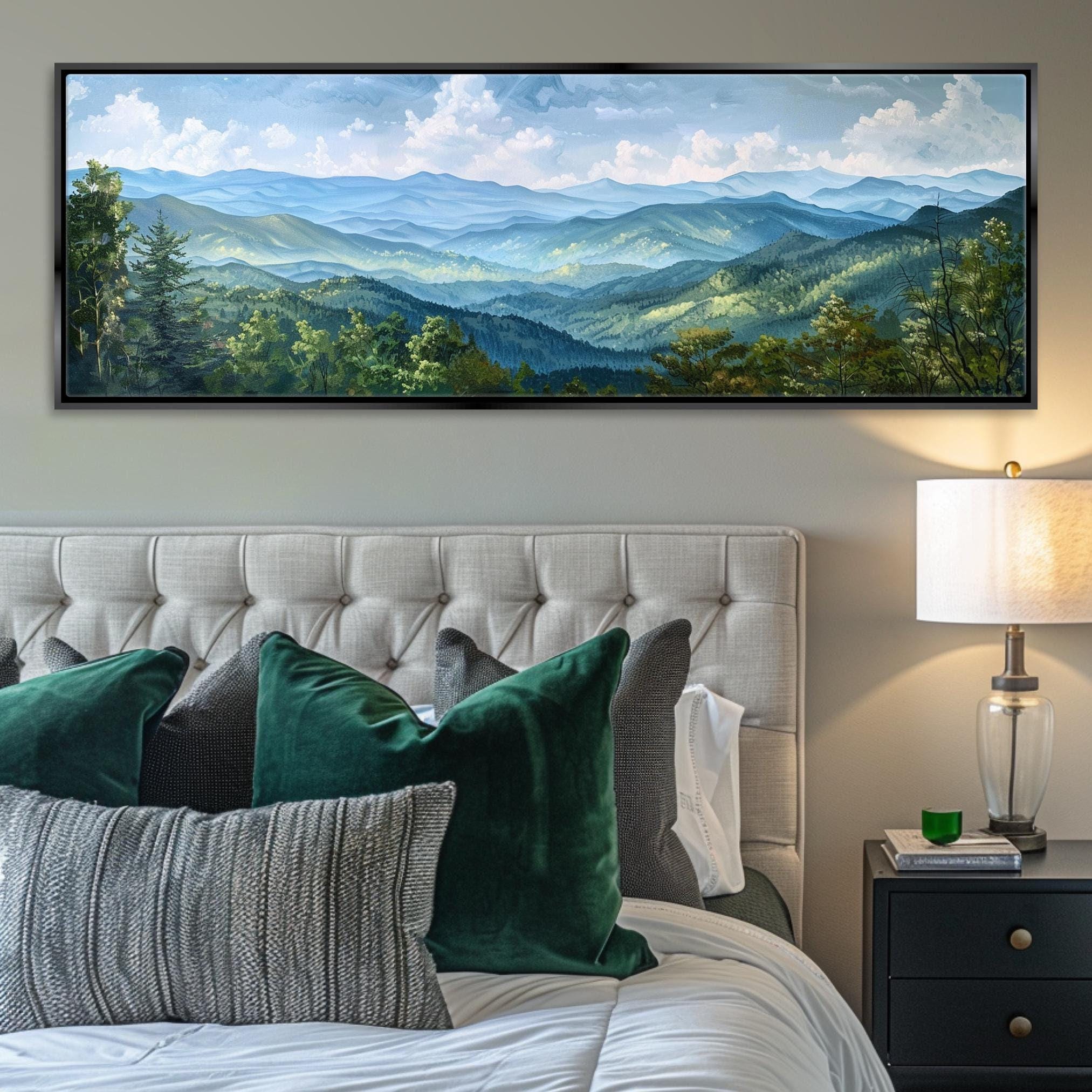a large landscape painting hanging on a wall above a bed with white tufted headboard. The painting depicts a scenic mountain range with lush green forests and a blue sky with white clouds.
