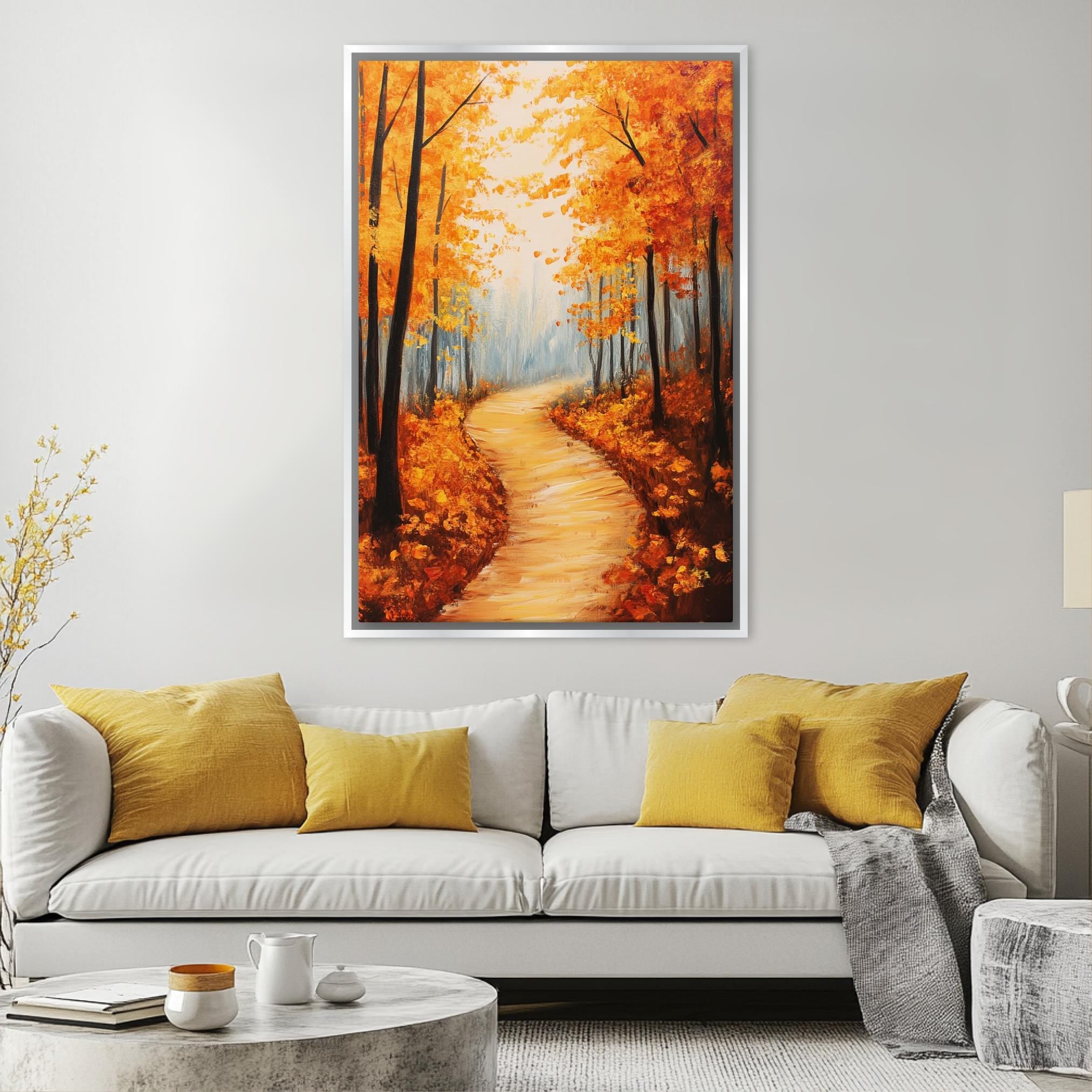 a large painting of a forest path with orange trees on the wall above a white couch with yellow pillows in a living room setting.