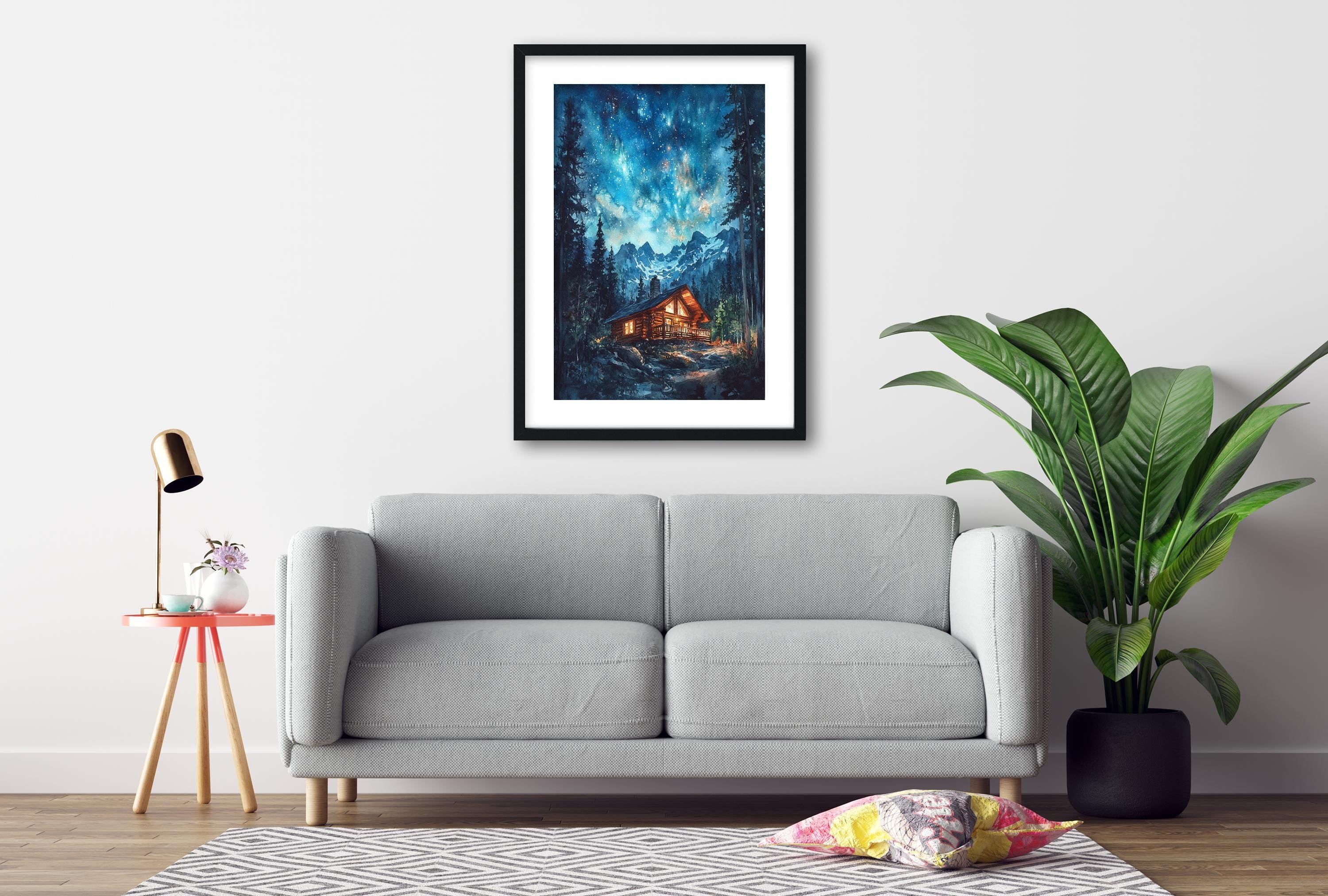 a cozy living room with a gray sofa, a framed painting of a cabin in the woods, a small table with a lamp, and a potted plant.