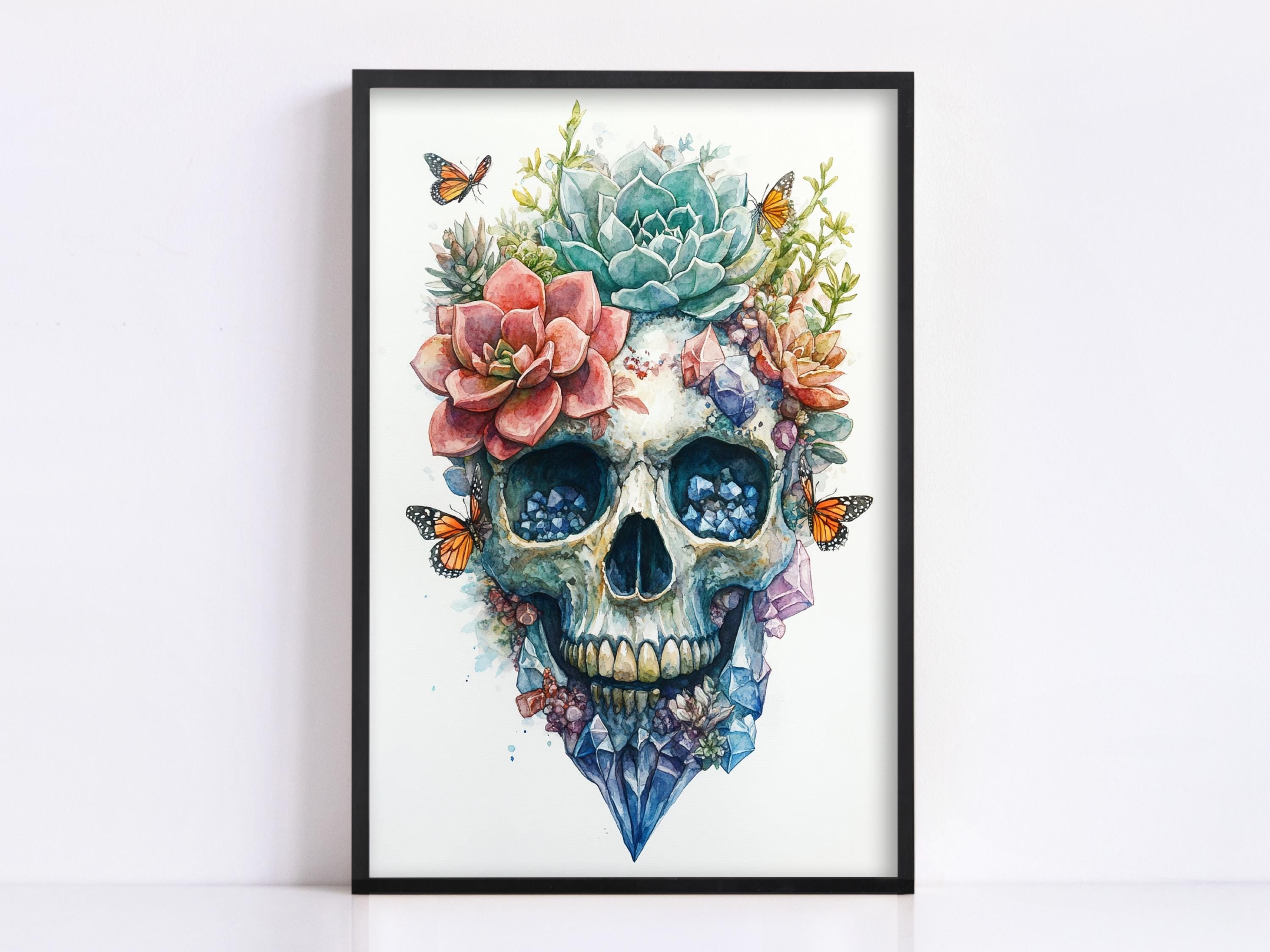 a framed artwork depicting a skull adorned with a floral arrangement, including a cactus, succulents, and colorful flowers.